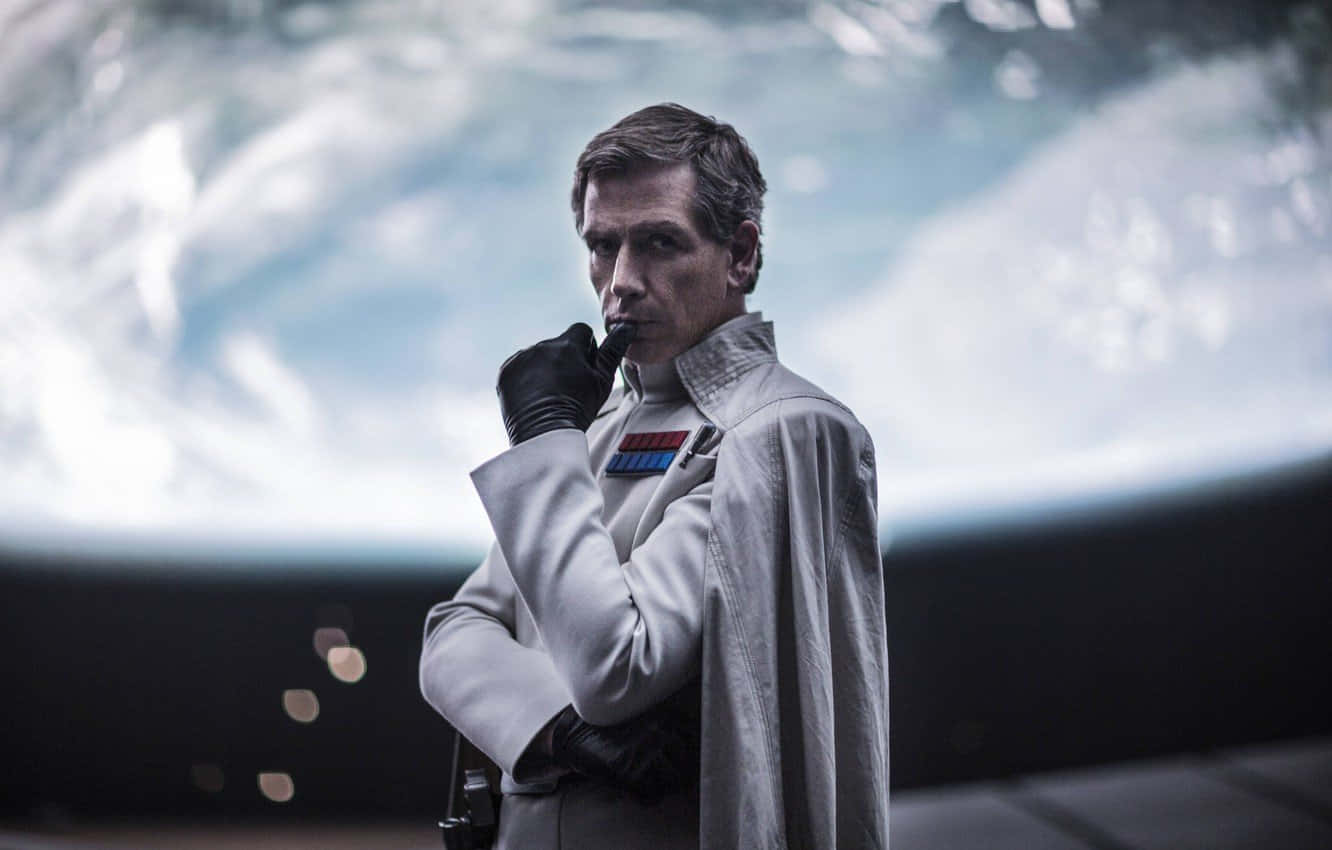 ben mendelsohn 桌布 壁紙 — 一個嚴肅的男人穿著白色帝國制服，戴著手套的手靠近嘴巴，站在模糊的未來背景前。