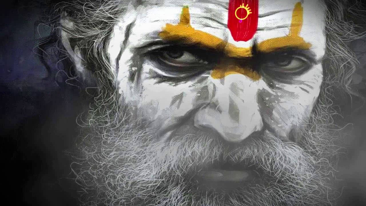 Aghori 桌布 壁紙 — 一個嚴肅面孔男人的特寫，臉上塗有白色顏料、黃色標記，額頭上有一個帶太陽符號的紅色眉心點。