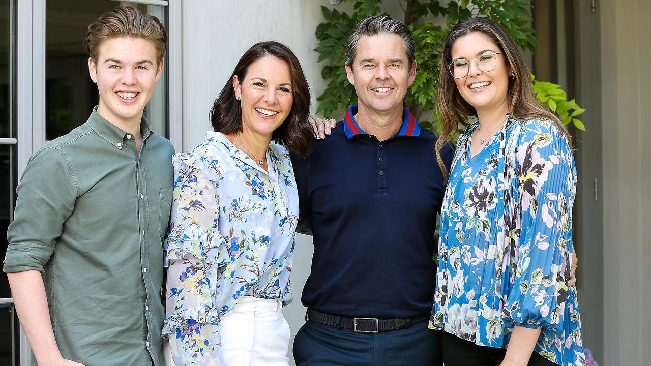 Family 桌布 壁紙 — 一個四口之家面帶微笑，在玻璃門附近的戶外一起擺姿勢，身後有綠植。