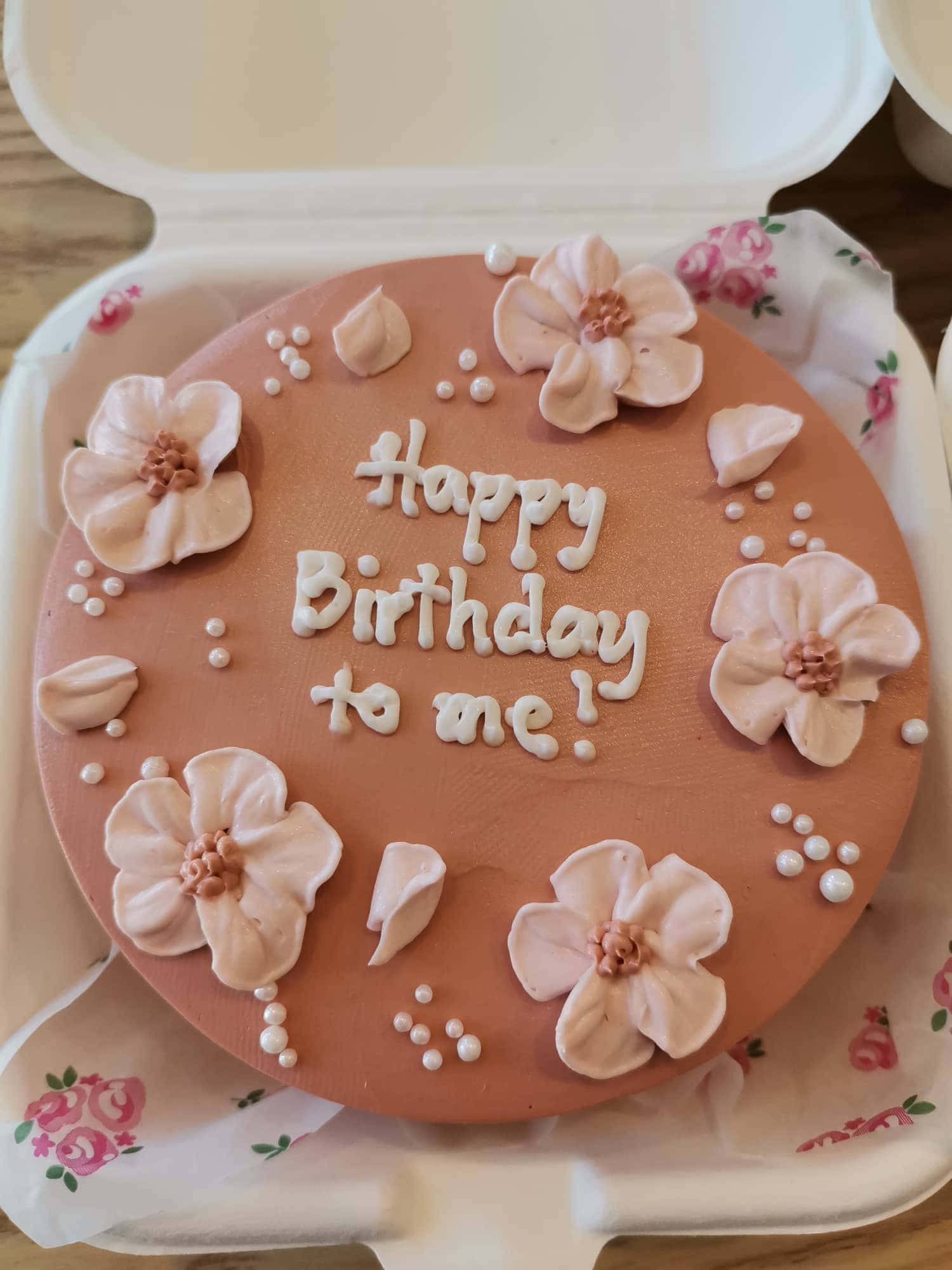 Happy Birthday To Me 桌布 壁紙 — 一個圓形蜜桃蛋糕，上面有白色糖霜花和「Happy Birthday to me!」字句，放在一個鋪有花卉圖案紙的外帶盒中。