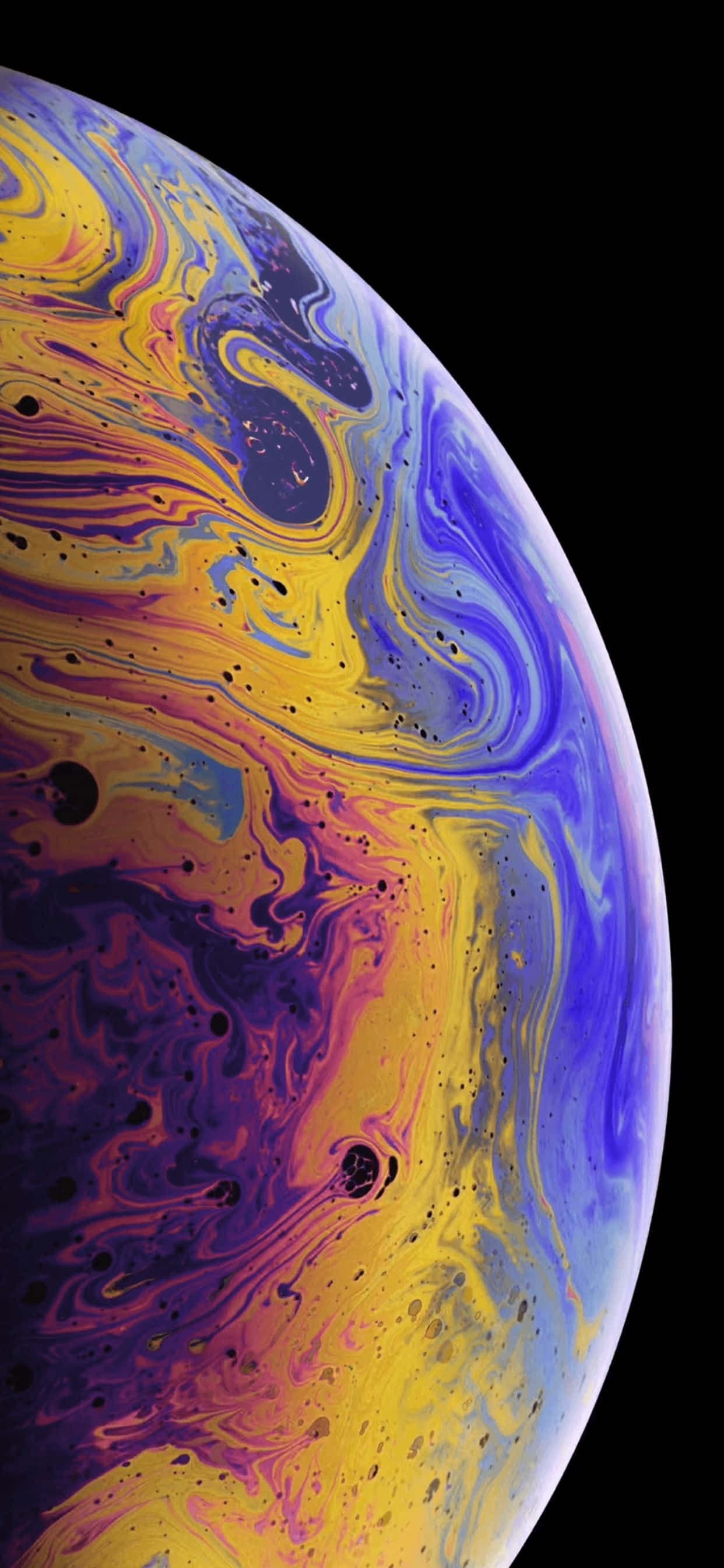 iPhone Xs Max 桌布 壁紙 — 一個在漆黑虛空中旋轉的宇宙球體，帶有鮮豔的黃色、紫色和藍色色調。