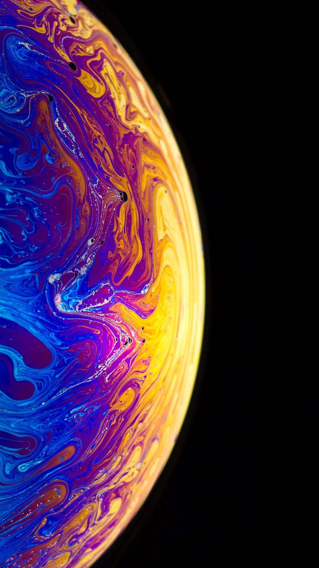 Apple iPhone Xs 桌布 壁紙 — 一個在漆黑虛空中旋轉的宇宙球體，帶有電光藍、紫色和金色黃。