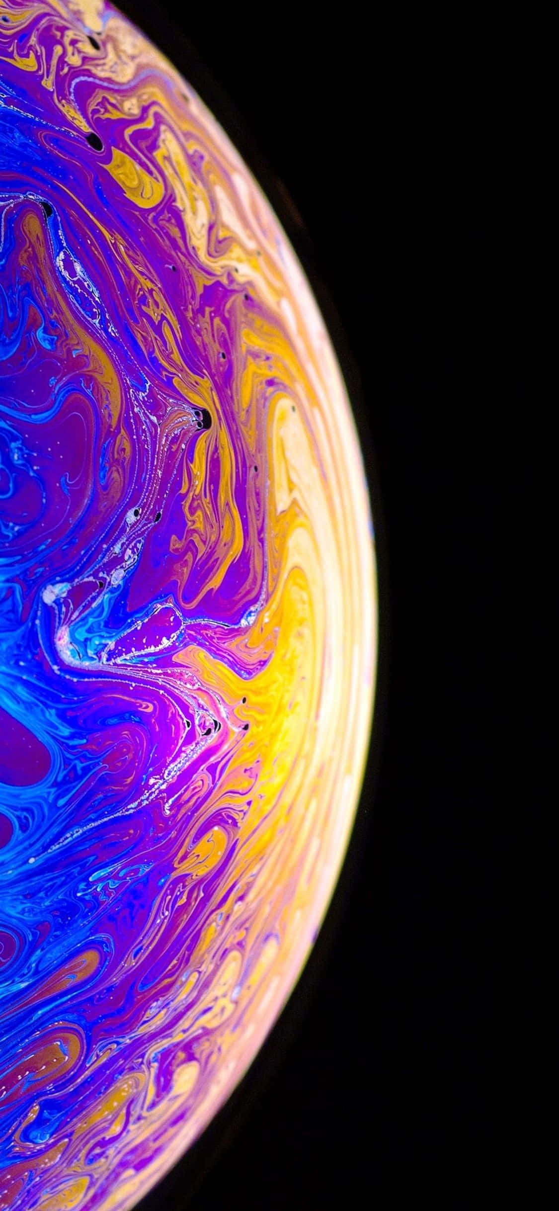 Designer iPhone 桌布 壁紙 — 一個在漆黑虛空中旋轉的宇宙球體，帶有電光紫、黃和藍色。