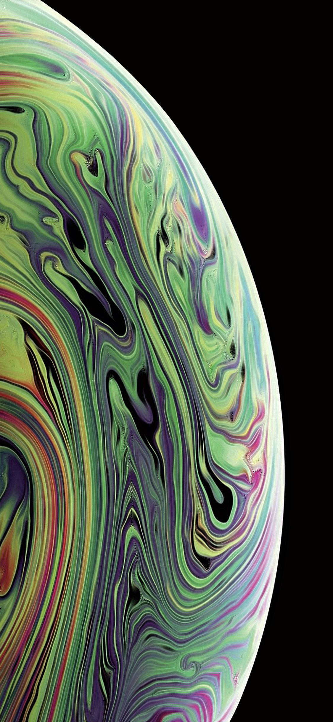 iPhone XS 桌布 壁紙 — 一個在黑色虛空中旋轉的抽象球體，帶有虹彩綠色、紫色和黃色。
