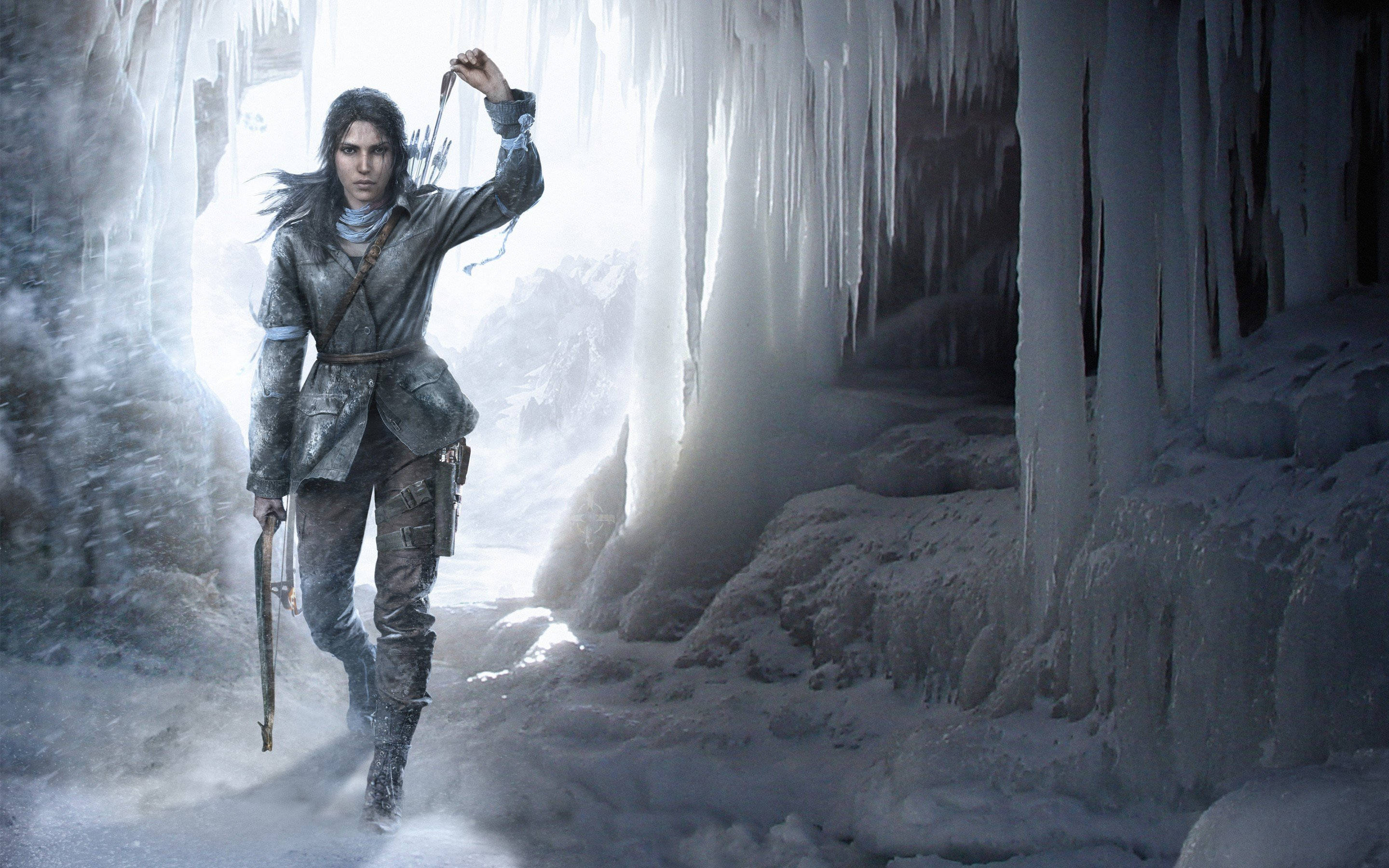 Tomb Raider Game 桌布 壁紙 — 一個堅定的冒險家穿過一個被背後強光照亮的冰凍洞穴，冰柱像水晶匕首一樣懸掛著。