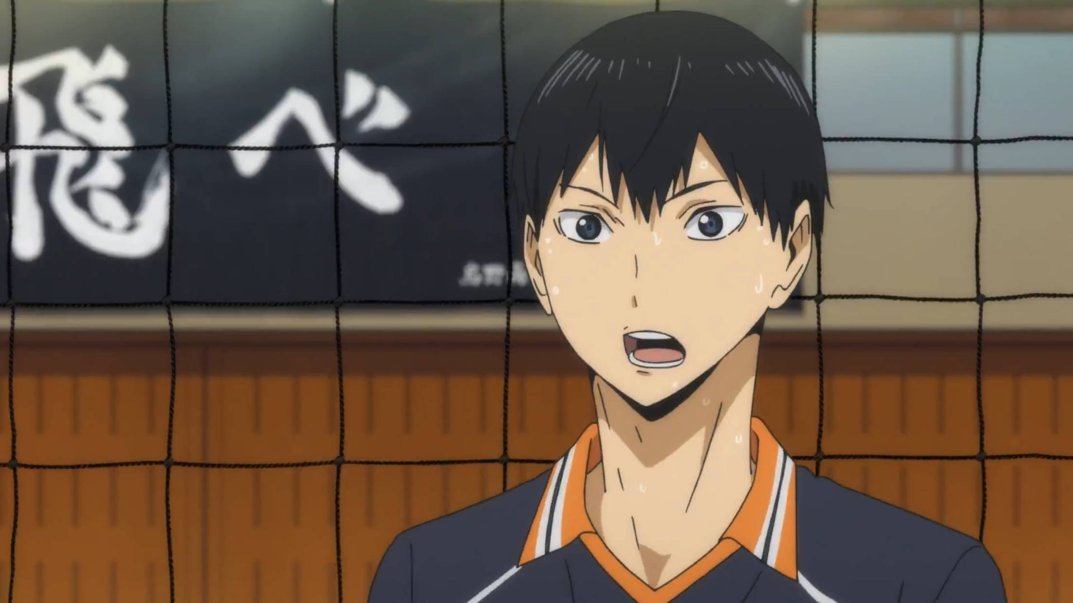 Kageyama 桌布 壁紙 — 一個堅定的動漫排球運動員，臉上流著汗水，站在室內場地的網後。