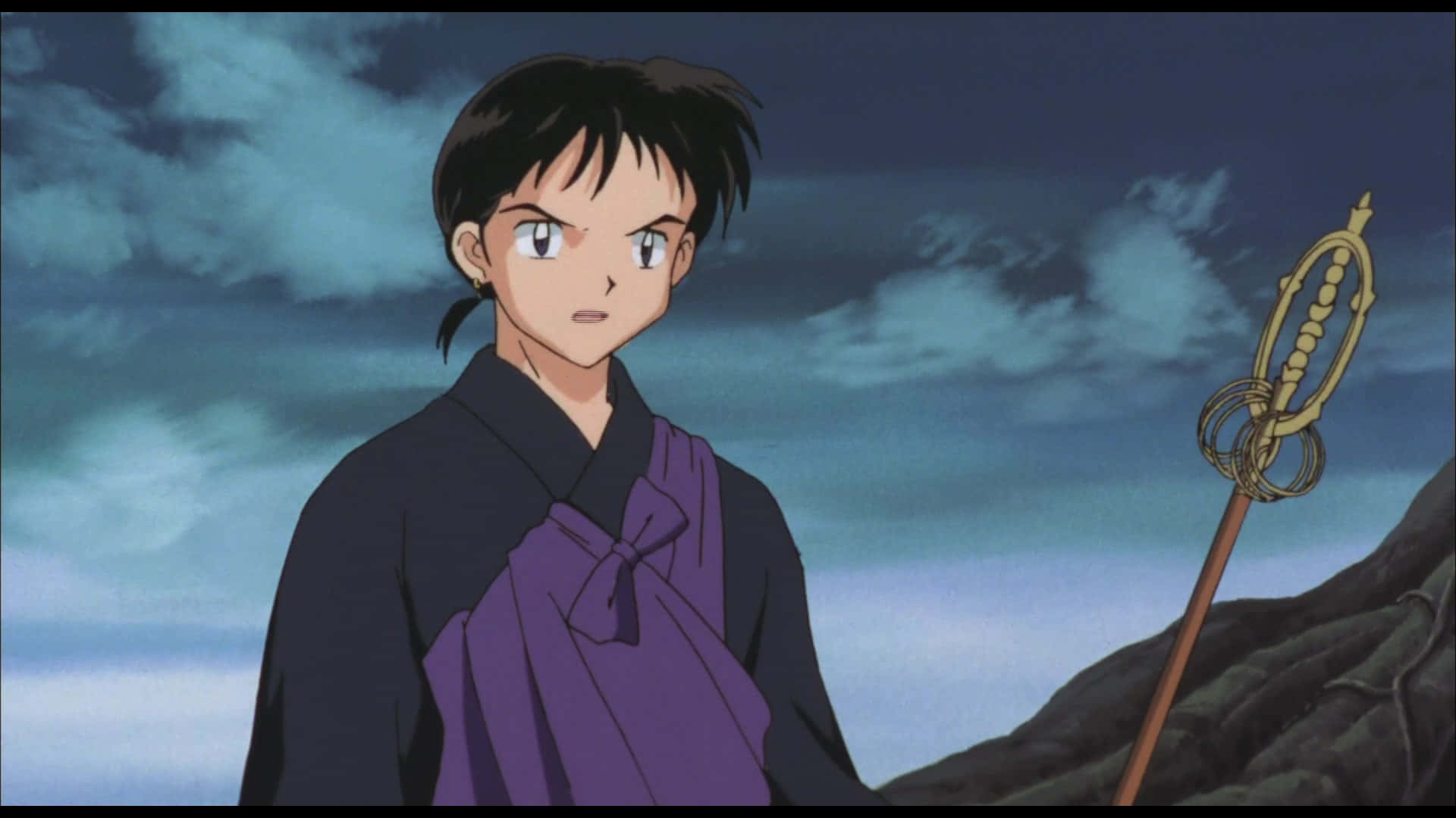 Miroku 桌布 壁紙 — 一個堅定的動漫角色穿著紫色和黑色長袍，在戶外手持金色法杖，背景是多雲的天空。