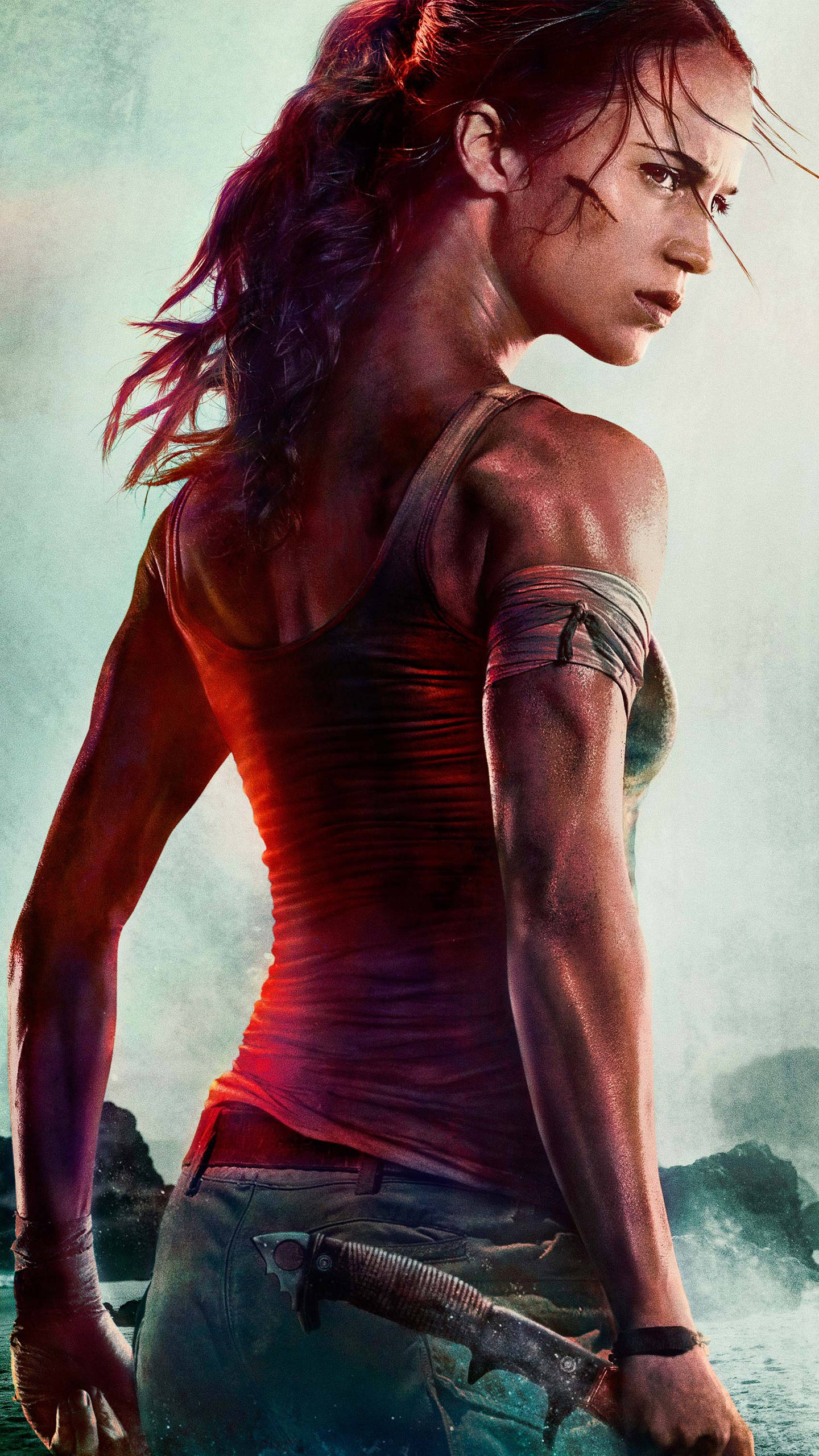 tomb raider iPhone 桌布 壁紙 — 一個堅定的女人，濕頭髮，腰間別著刀，站在霧氣繚繞的岩石地形中，光線戲劇性。