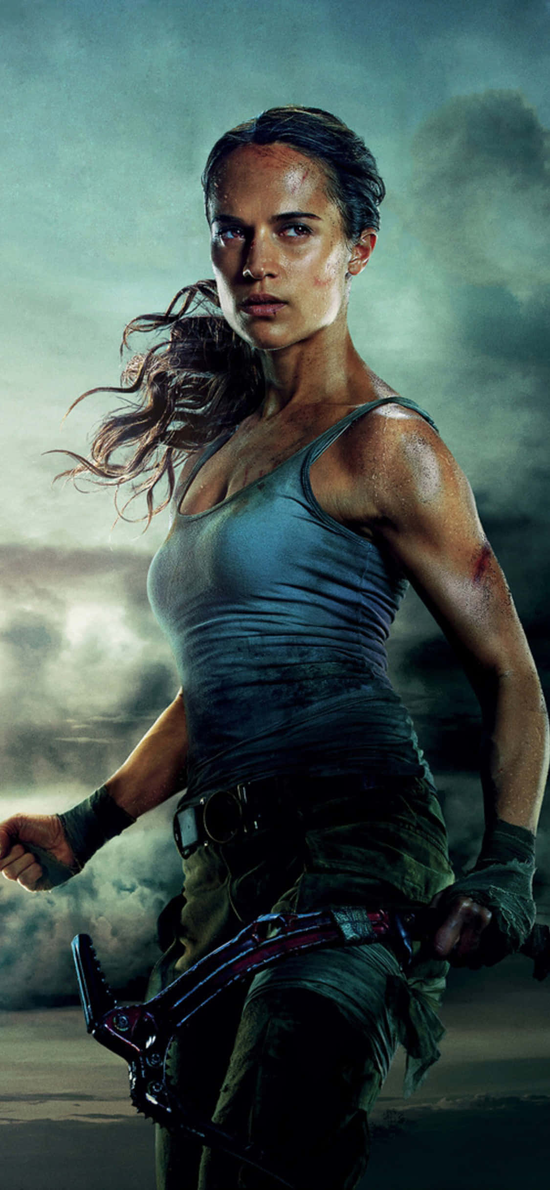 tomb raider iPhone 桌布 壁紙 — 一個堅定的女人，頭髮被風吹亂，手持武器，在暴風雨的天空下，身處一個粗獷的冒險場景中。