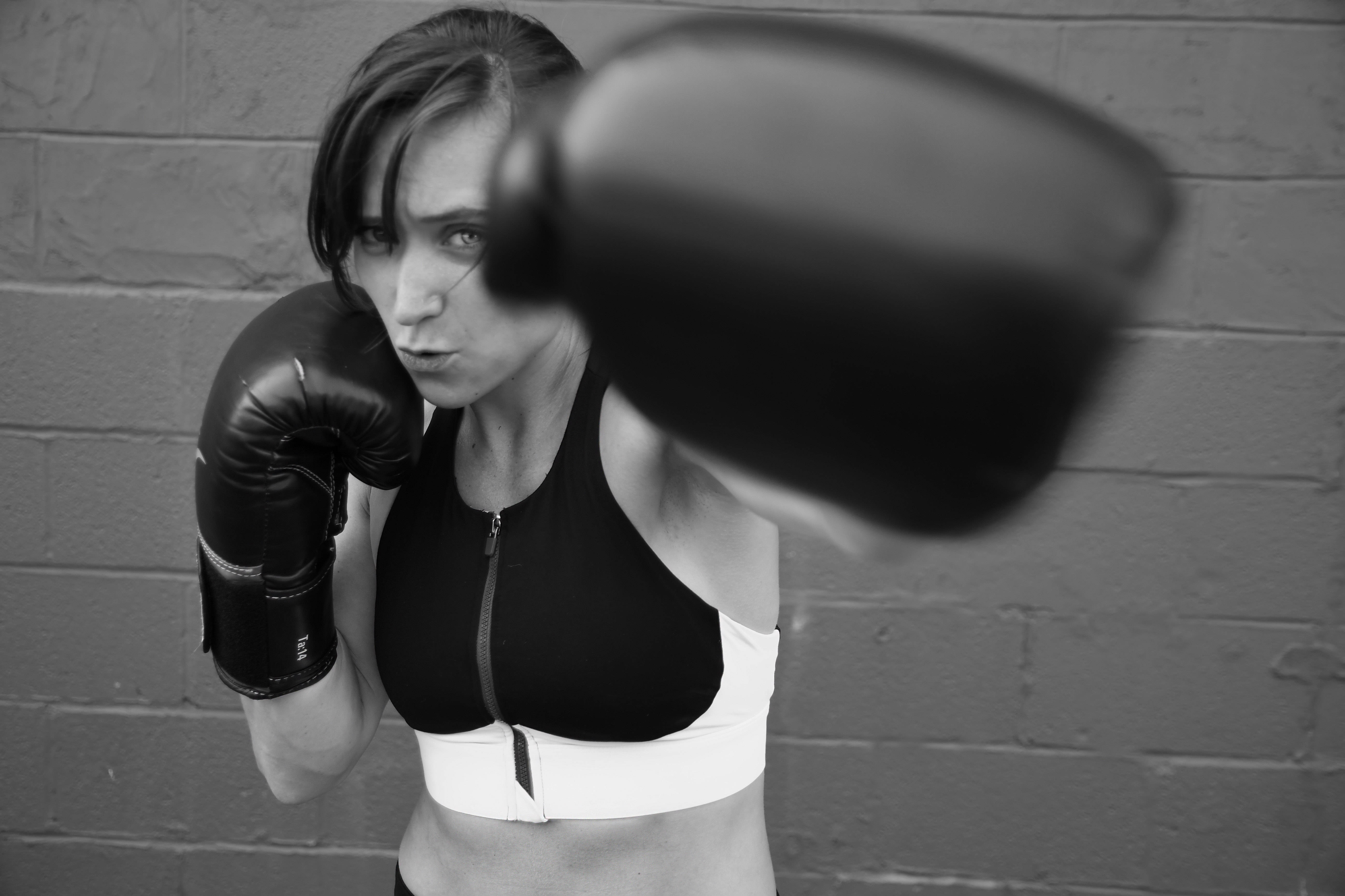 Boxing 桌布 壁紙 — 一個堅定的女人戴著拳擊手套，在粗糙的黑白照片中向前擊打磚牆。