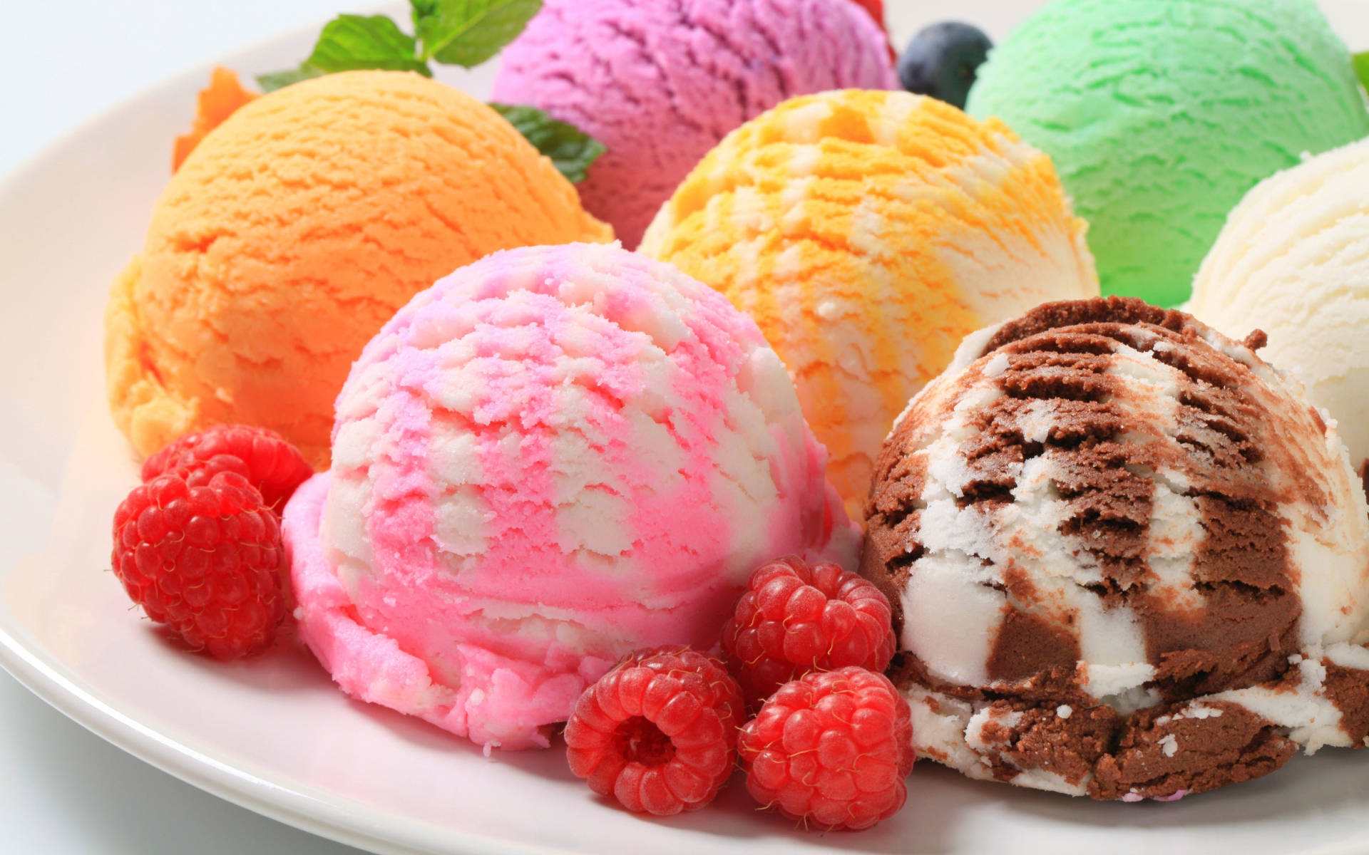 Berry 桌布 壁紙 — 一個堆滿色彩繽紛、口味鮮明的冰淇淋球的盤子，上面裝飾著新鮮的覆盆子和薄荷。