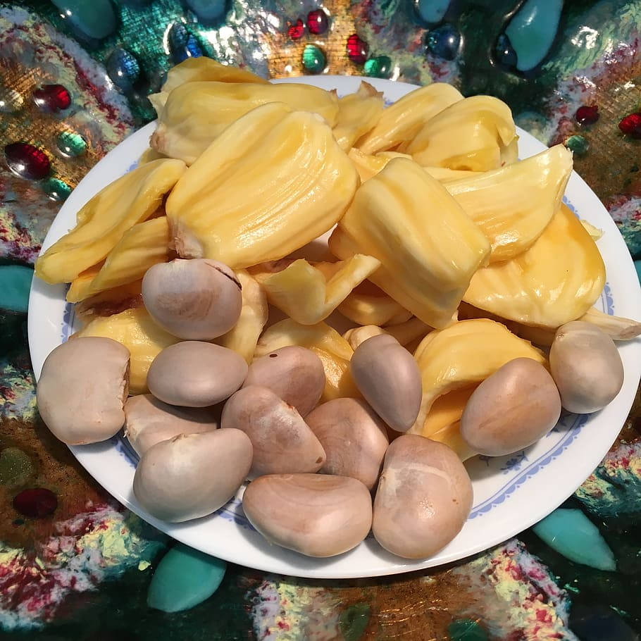 Fruit 桌布 壁紙 — 一個堆滿金黃色波羅蜜果肉和淡色種子的盤子，放在由彩色珠子和玻璃組成的閃閃發光馬賽克上。