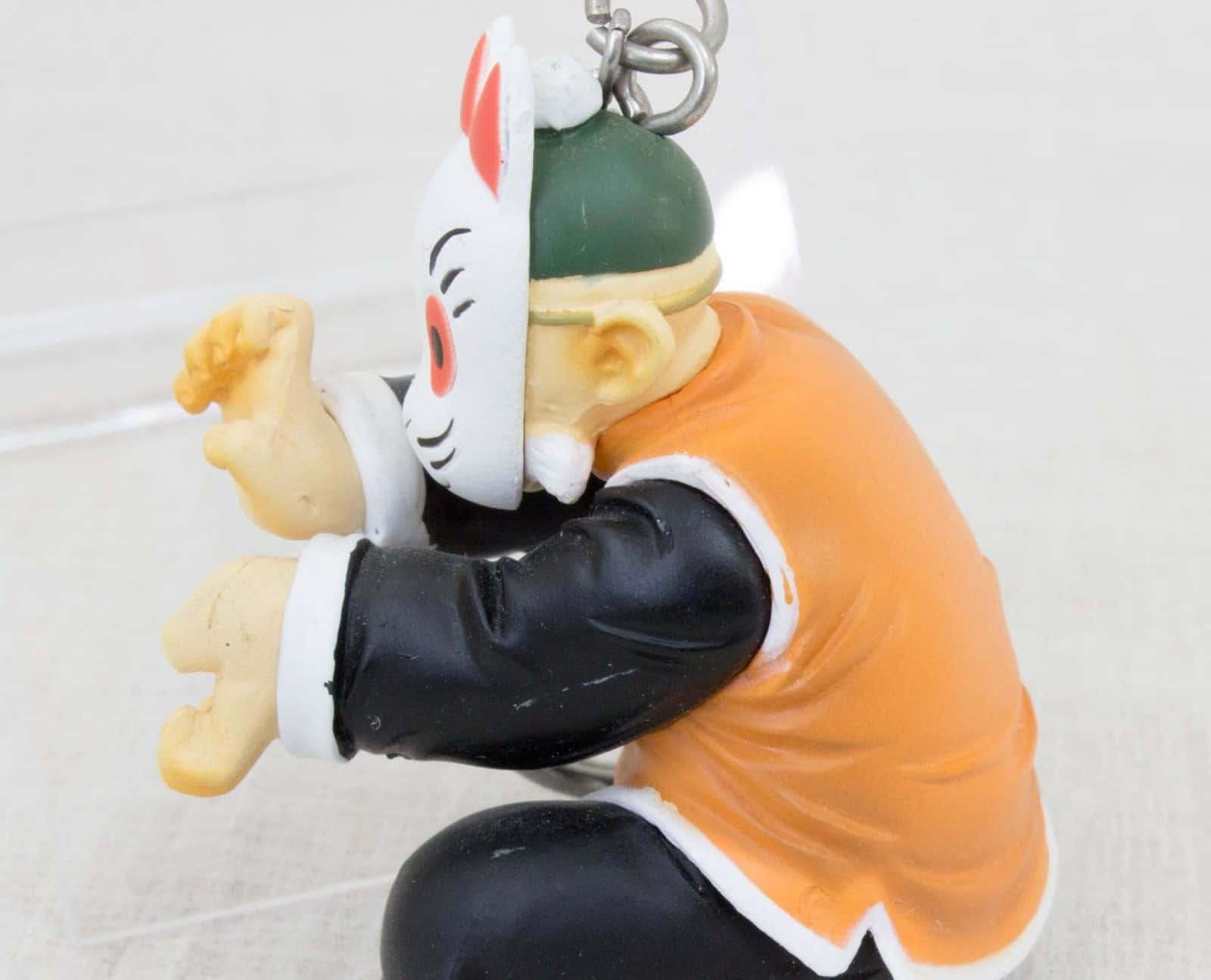 Grandpa Gohan 桌布 壁紙 — 一個塑膠動漫鑰匙圈公仔的特寫，穿著橙色和黑色的服裝，戴著白色兔子面具。