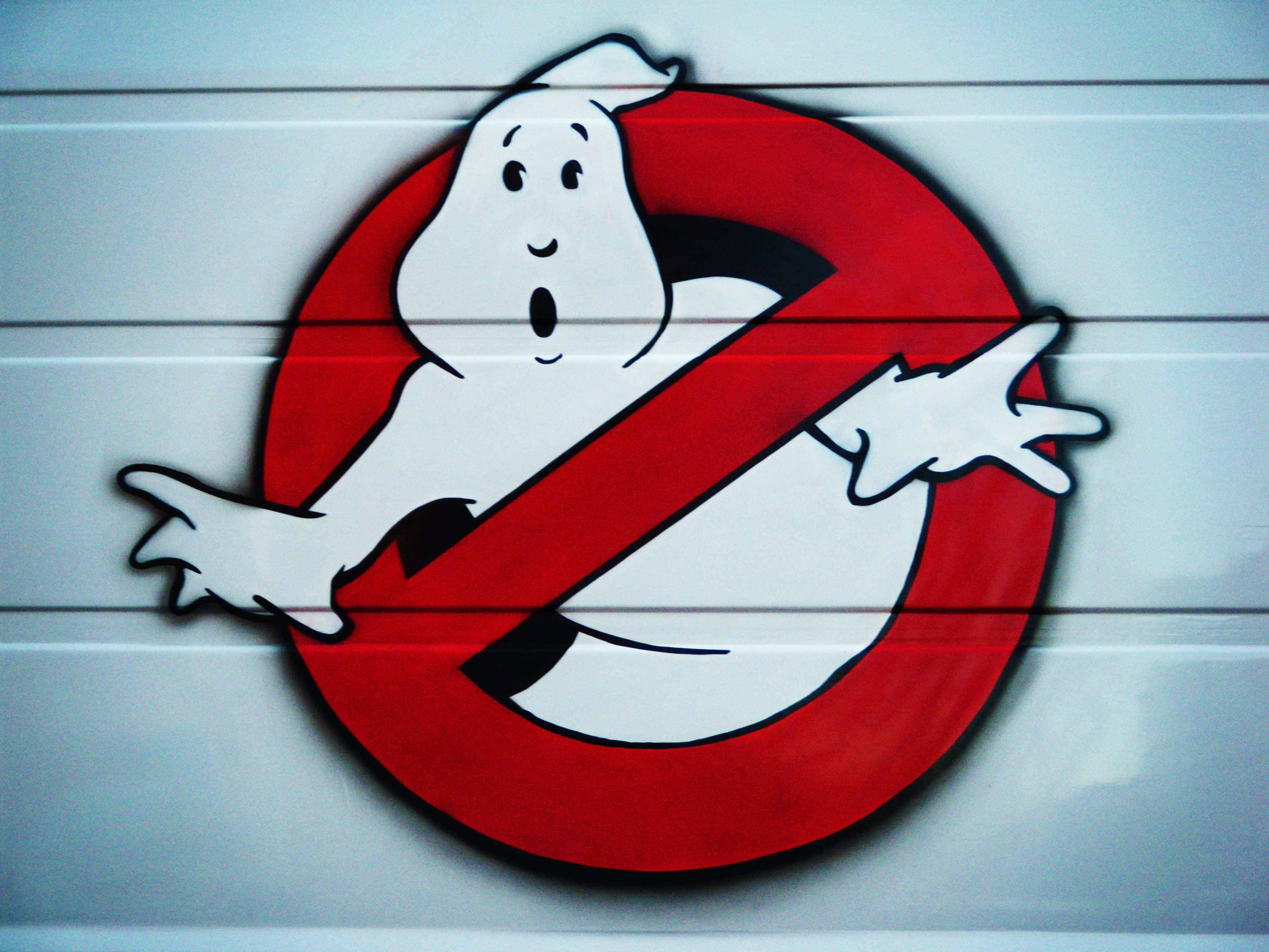 魔鬼剋星 桌布 壁紙 — 一個塗鴉的Ghostbusters標誌，在白色鑲板牆上有一個紅色禁止符號，裡面有一隻驚訝的鬼魂。