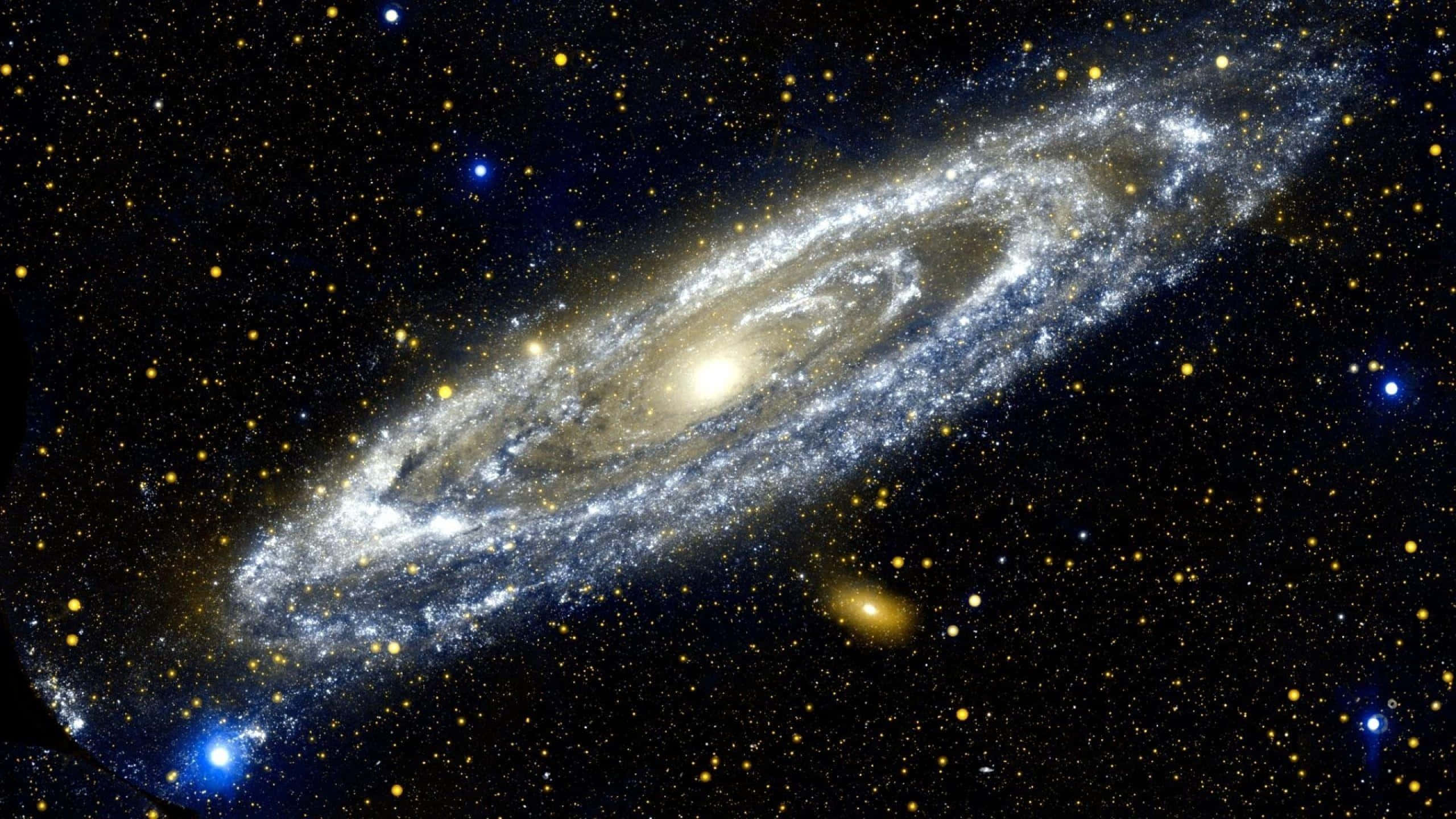 1440p 桌布 壁紙 — 一個壯麗的螺旋星系在佈滿星星的宇宙背景下發出金色和藍色的光芒。