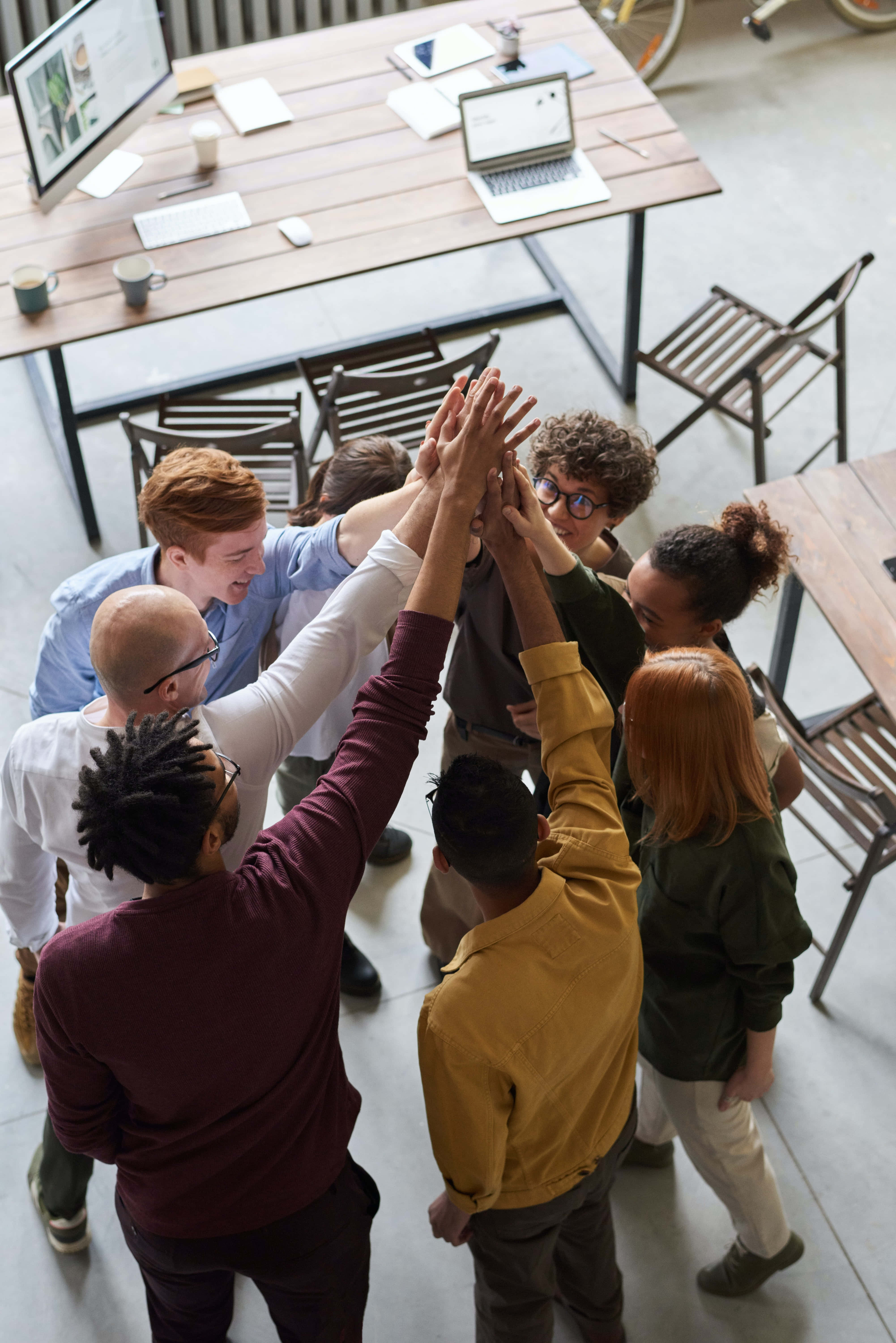 Teamwork 桌布 壁紙 — 一個多元化的同事團隊在現代開放式辦公室空間中熱情地擊掌。