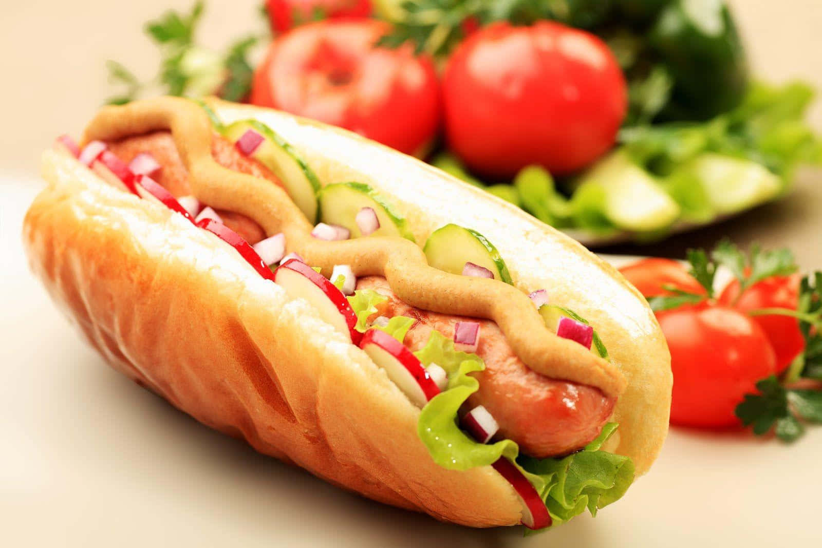 Hot Dog 桌布 壁紙 — 一個多汁熱狗的特寫，放在軟麵包上，加上芥末、番茄醬、洋蔥和新鮮蔬菜。