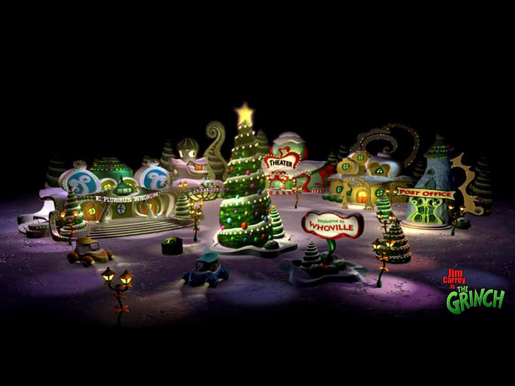 The Grinch 桌布 壁紙 — 一個夢幻的雪覆蓋Whoville小鎮夜景，黑暗天空下閃爍的建築和節日樹木。