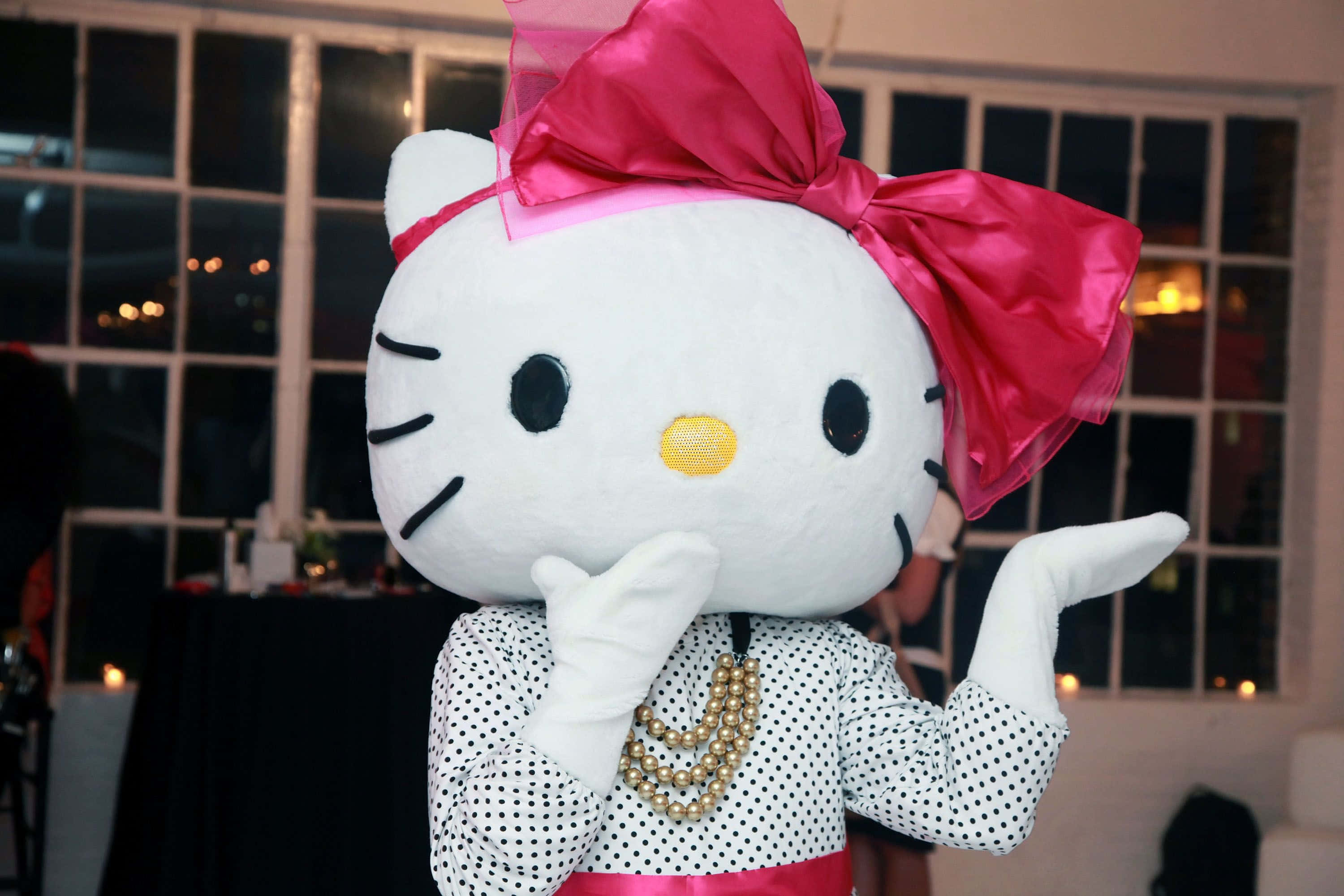 Hello Kitty 桌布 壁紙 — 一個大型Hello Kitty吉祥物穿著圓點襯衫和珍珠項鍊，夜晚在窗前單手托腮擺姿勢。