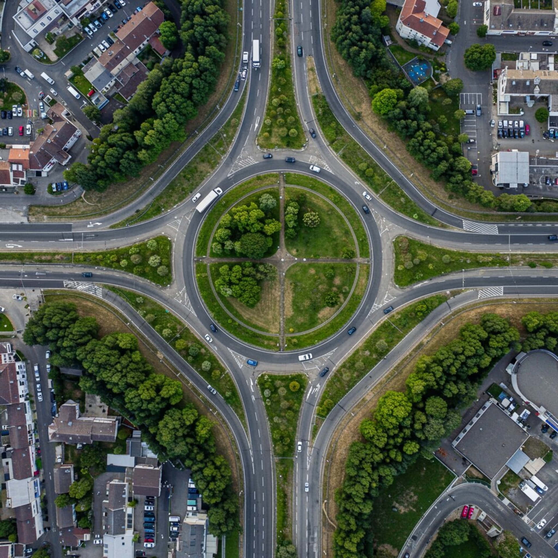 City from above 壁紙 — 一個大型圓環的鳥瞰圖，中央有茂密的綠化，周圍是道路、汽車和住宅建築。