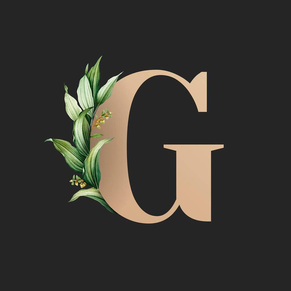 g 桌布 壁紙 — 一個大型米色字母G，裝飾著綠色葉片和小黃花，背景深色。