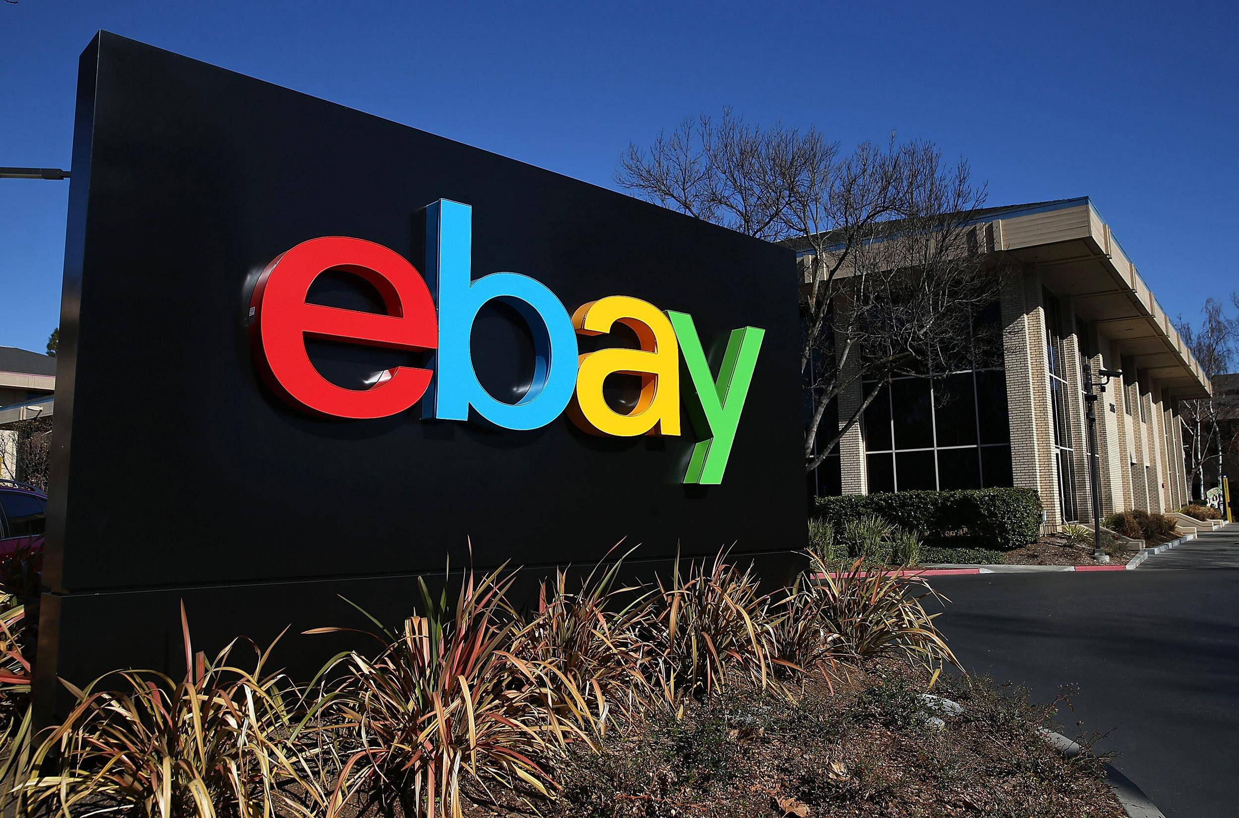 eBay 桌布 壁紙 — 一個大型色彩繽紛的eBay標誌招牌，在晴朗的藍天下，醒目地矗立在一棟現代辦公大樓前。