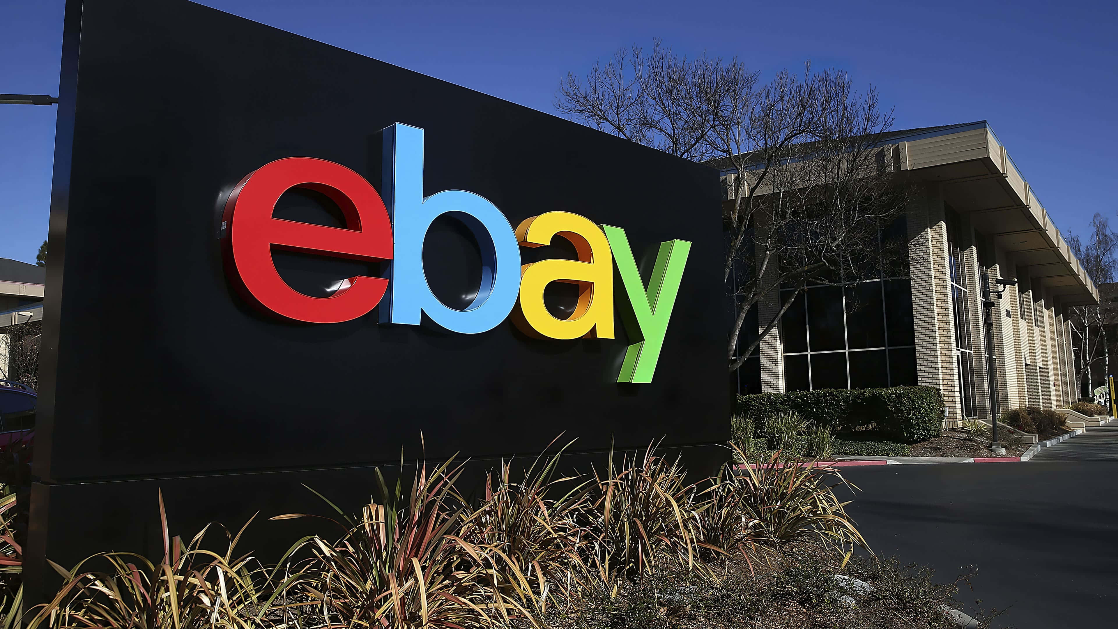 eBay 桌布 壁紙 — 一個大型色彩繽紛的eBay標誌牌聳立在現代辦公大樓外，在晴朗的藍天下格外顯眼。