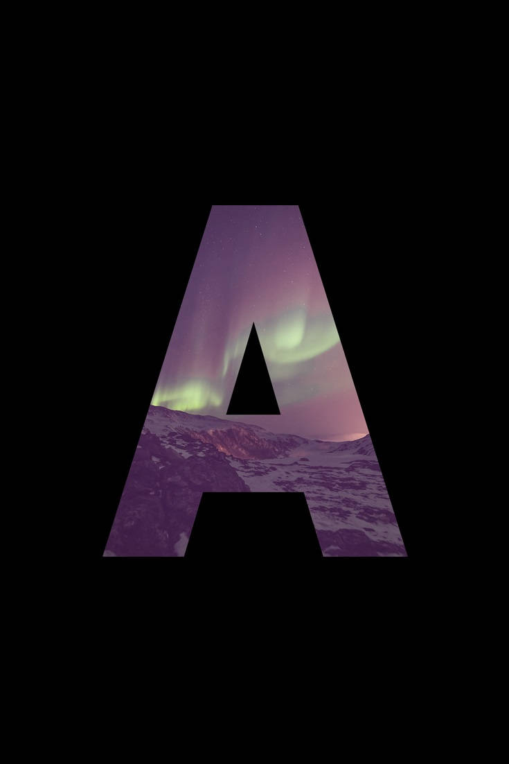 Letter A 桌布 壁紙 — 一個大字母A框住一個被雪覆蓋的山景，下方是充滿活力的北極光，在繁星點點的夜空中閃爍著綠色和紫色。
