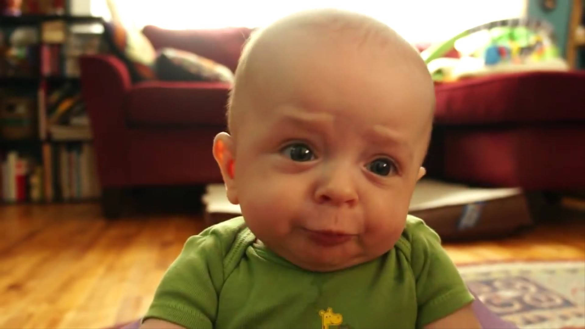 Funny Baby 桌布 壁紙 — 一個大眼嘟嘴的嬰兒近距離特寫，室內穿著綠色襯衫。