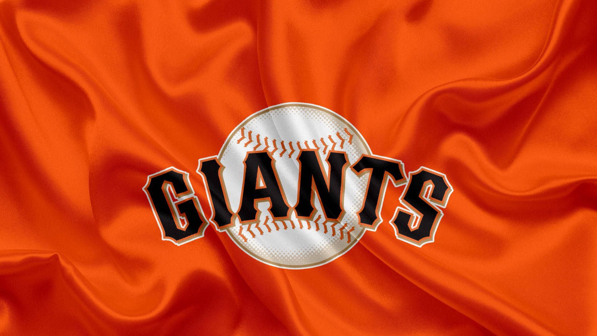 Giants 桌布 壁紙 — 一個大膽的 Giants 棒球標誌，居中在豐富的橙色緞面布料上，帶有戲劇性的褶皺和高光。