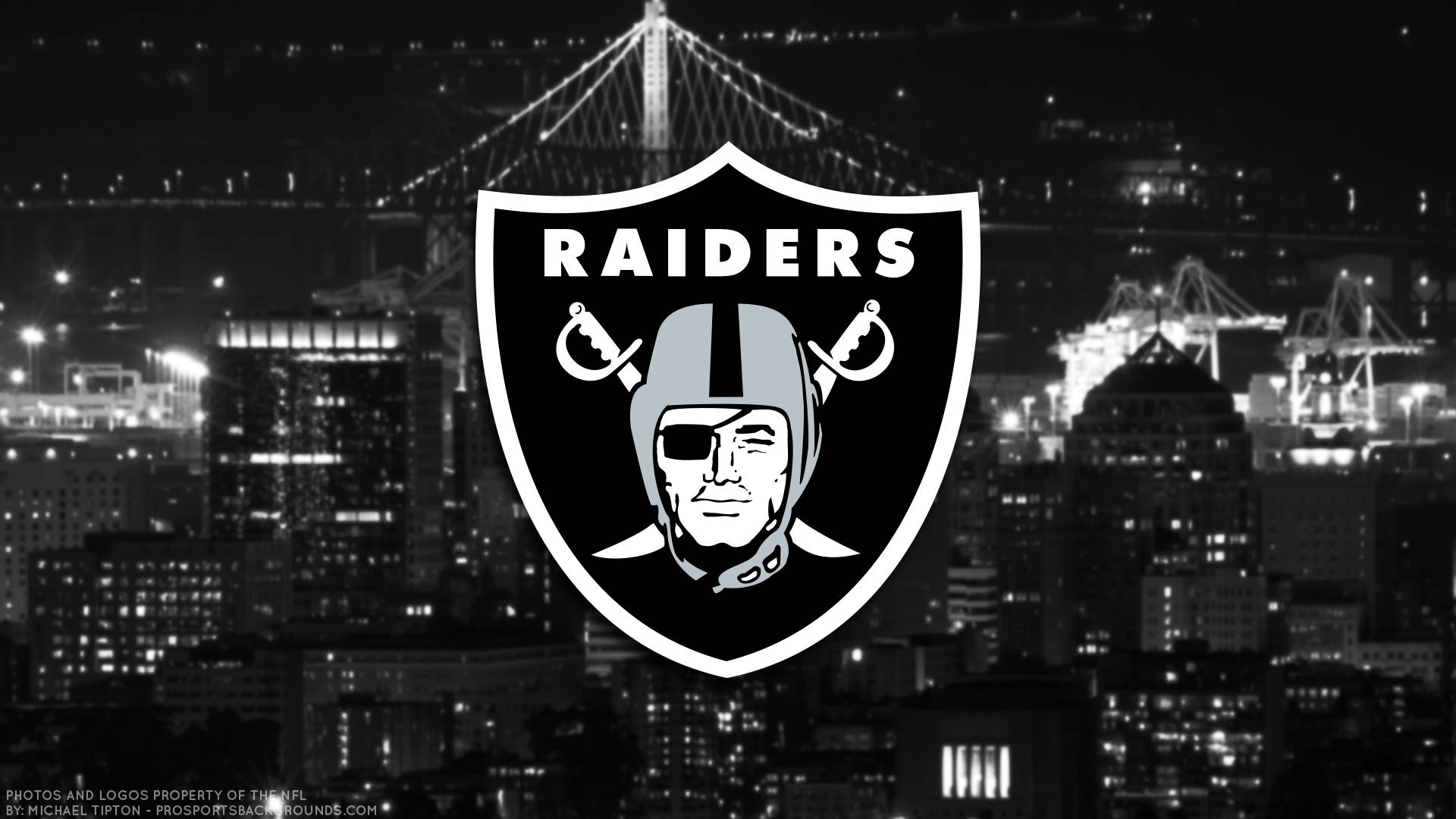 突襲者 桌布 壁紙 — 一個大膽的 Raiders 標誌主導了夜晚的單色城市景觀，背景中有燈光璀璨的橋樑和港口起重機。
