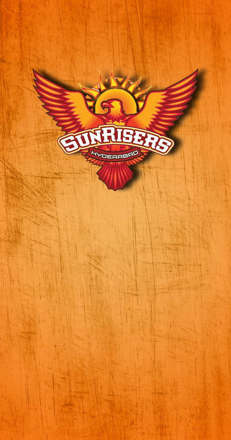 海德拉巴日出者 桌布 壁紙 — 一個大膽的 sunrisers hyderabad 標誌，中心是一個火焰鳳凰標誌，位於有紋理的橙色背景上。