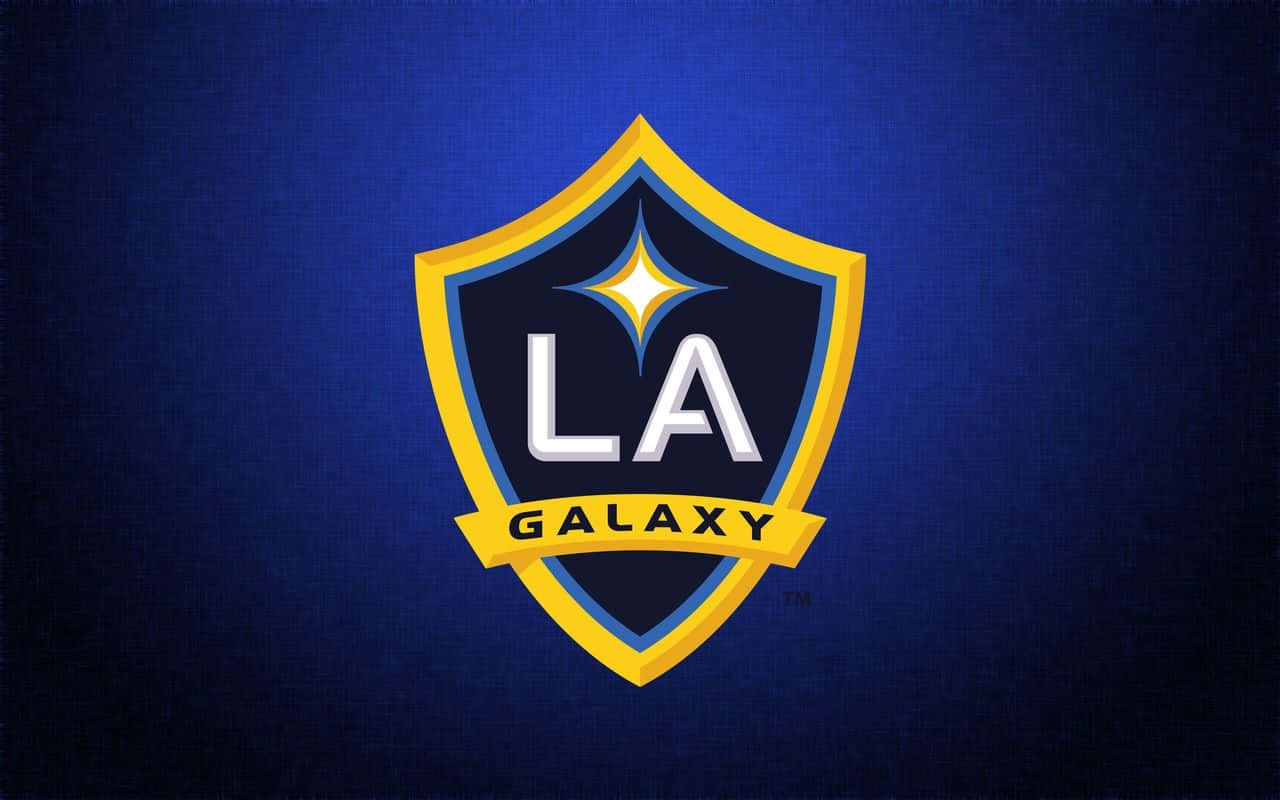 足球 桌布 壁紙 — 一個大膽的LA Galaxy足球隊標誌，置中在帶有紋理的深藍色背景上，並有黃色和白色點綴。