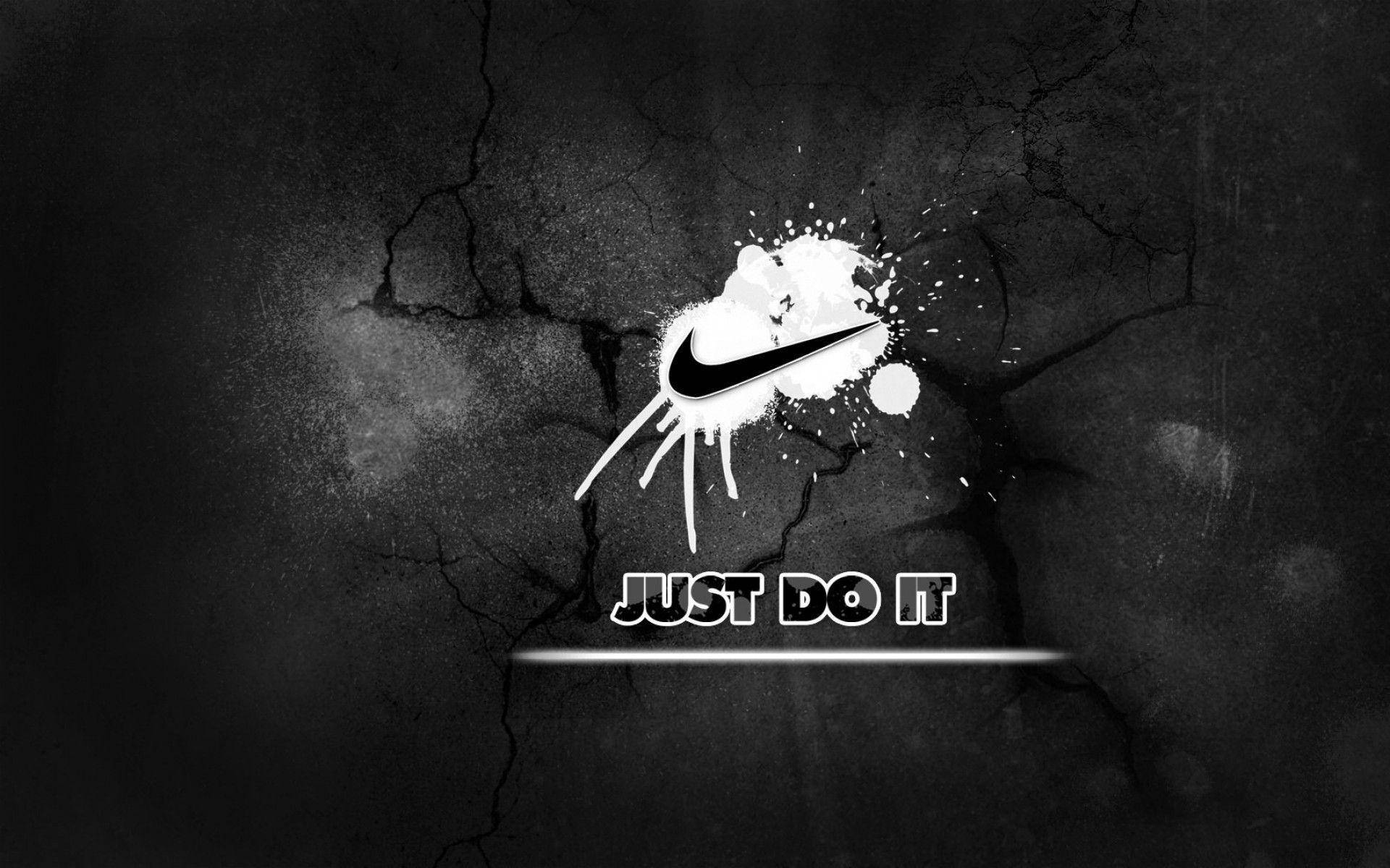 Just Do It 桌布 壁紙 — 一個大膽的Nike勾勾和「JUST DO IT」文字從白色油漆噴濺中迸發，背景是裂開的黑色混凝土牆。