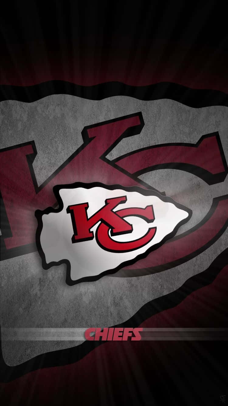 Kansas City Chiefs Logo 桌布 壁紙 — 一個大膽的堪薩斯城酋長標誌從帶有紅色和黑色射線的紋理灰色背景中散發出來。