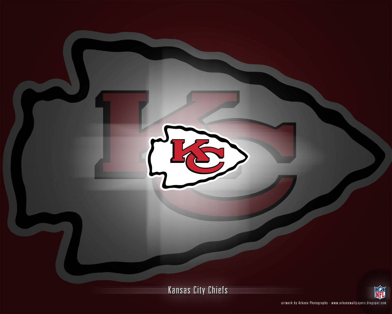 Kansas City Chiefs Cool 桌布 壁紙 — 一個大膽的堪薩斯城酋長隊標誌在深栗色背景上以紅、白、灰色發光，並帶有微妙的箭頭輪廓。