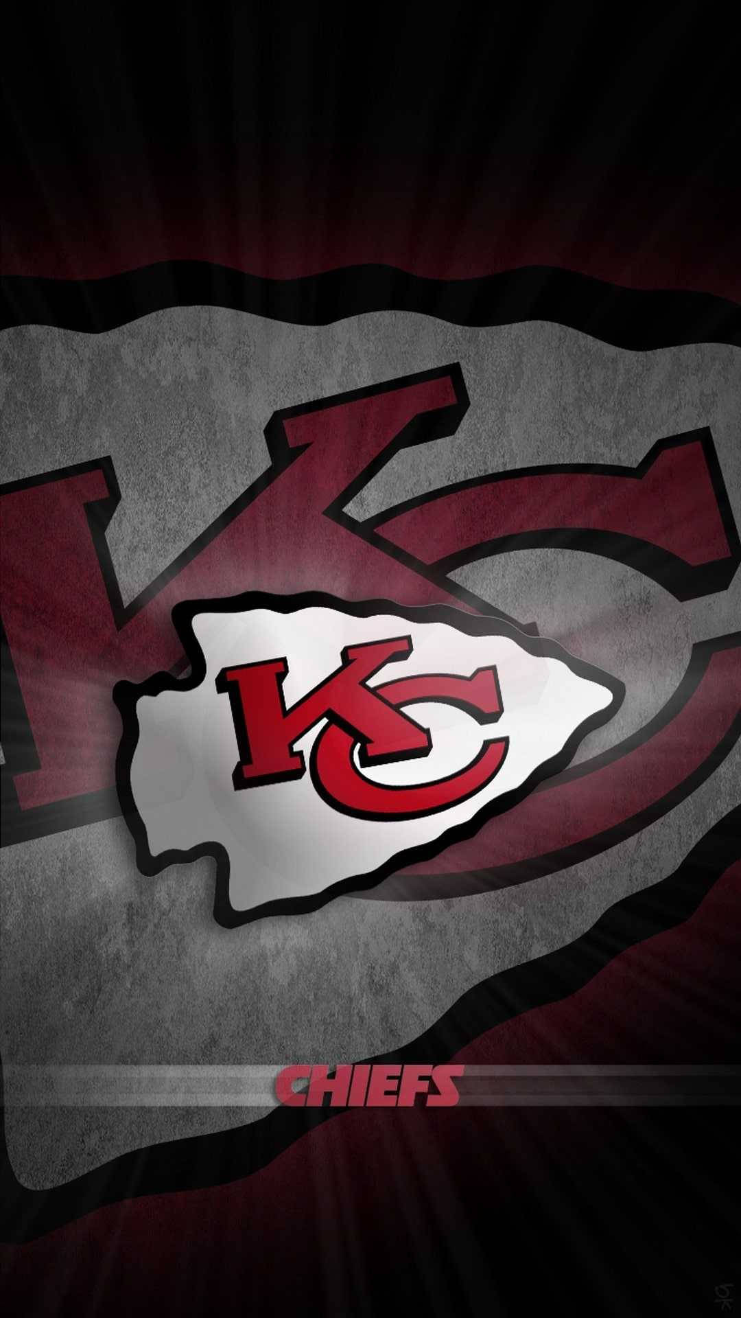 Kansas City Chiefs Cool 桌布 壁紙 — 一個大膽的堪薩斯城酋長隊標誌從帶有紅色和黑色點綴的紋理灰色背景中散發出來。