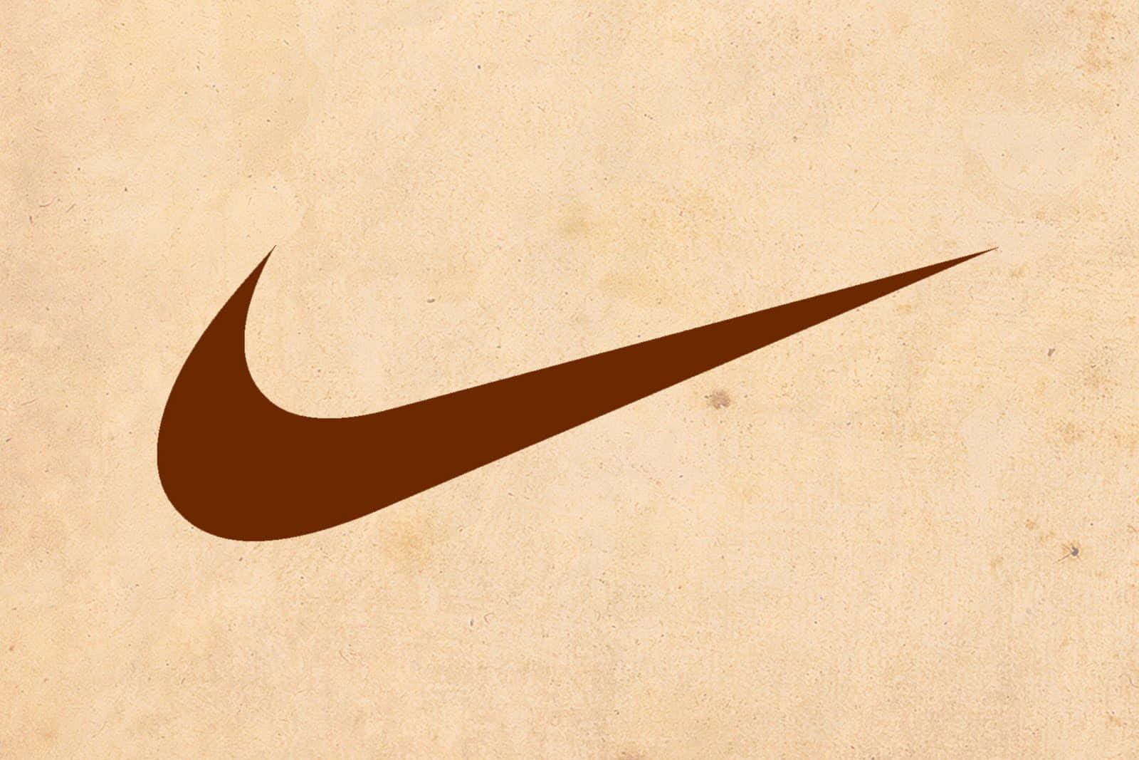 Nike 桌布 壁紙 — 一個大膽的棕色Nike swoosh標誌位於帶有細微斑點的紋理米色紙張背景上。