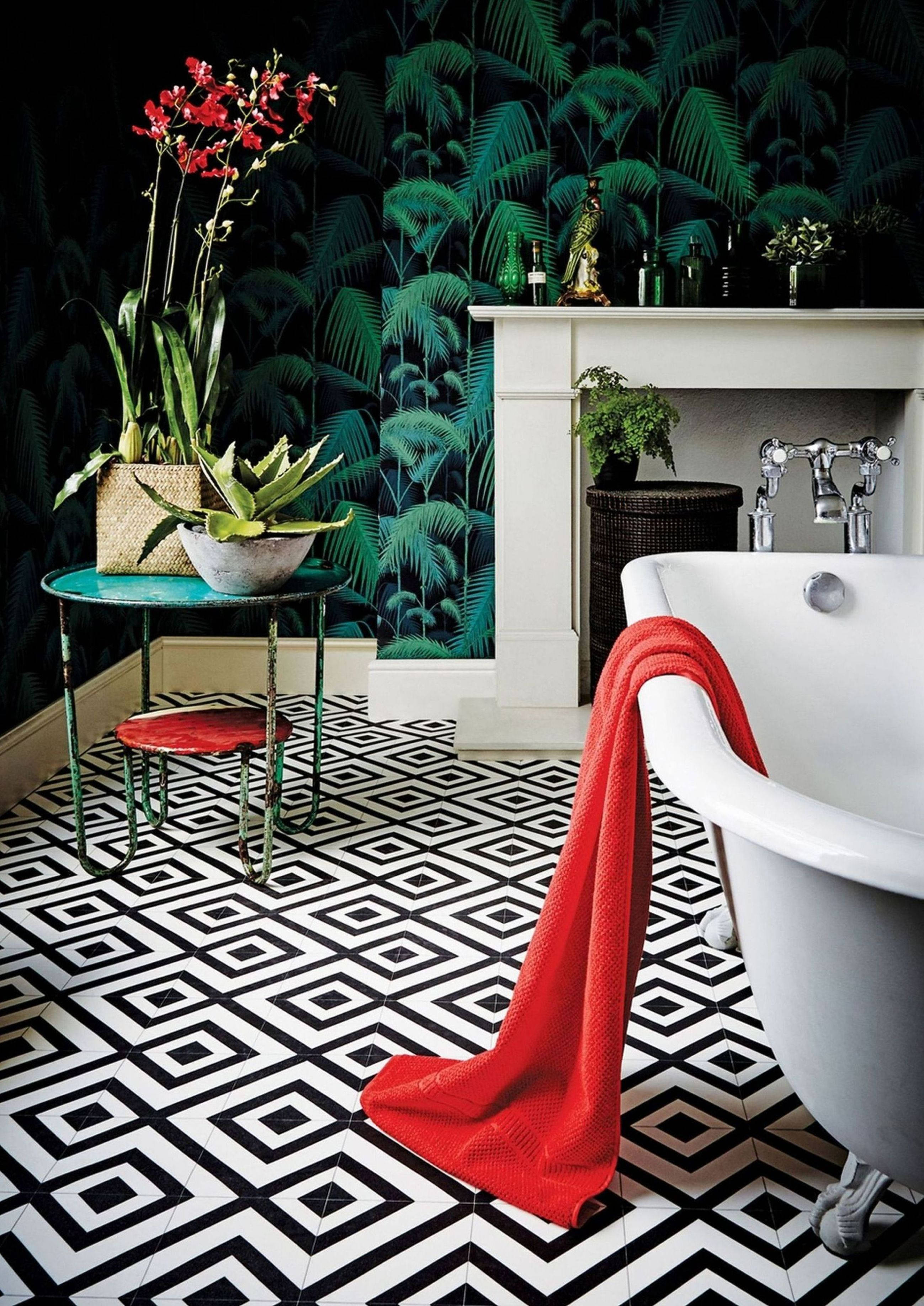 Floor Tiles 桌布 壁紙 — 一個大膽的浴室，配有黑白幾何瓷磚、熱帶綠色壁紙，以及一條鮮紅色毛巾搭在白色爪腳浴缸上。