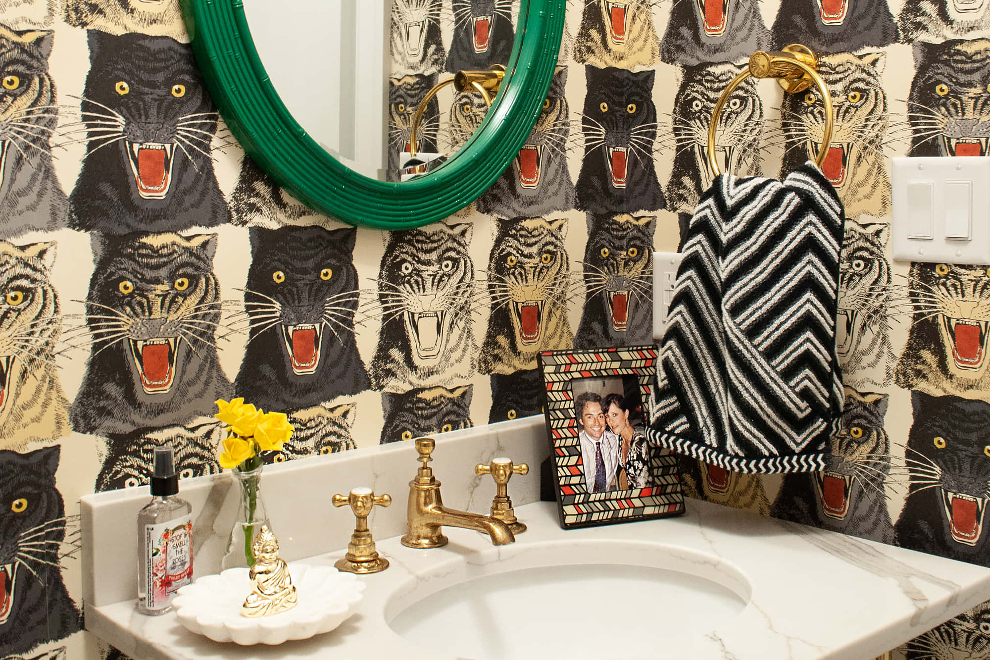 Bathroom Decor 桌布 壁紙 — 一個大膽的浴室，配有黑色豹紋壁紙、金色配件和白色大理石洗手盆上方的綠色鏡子。