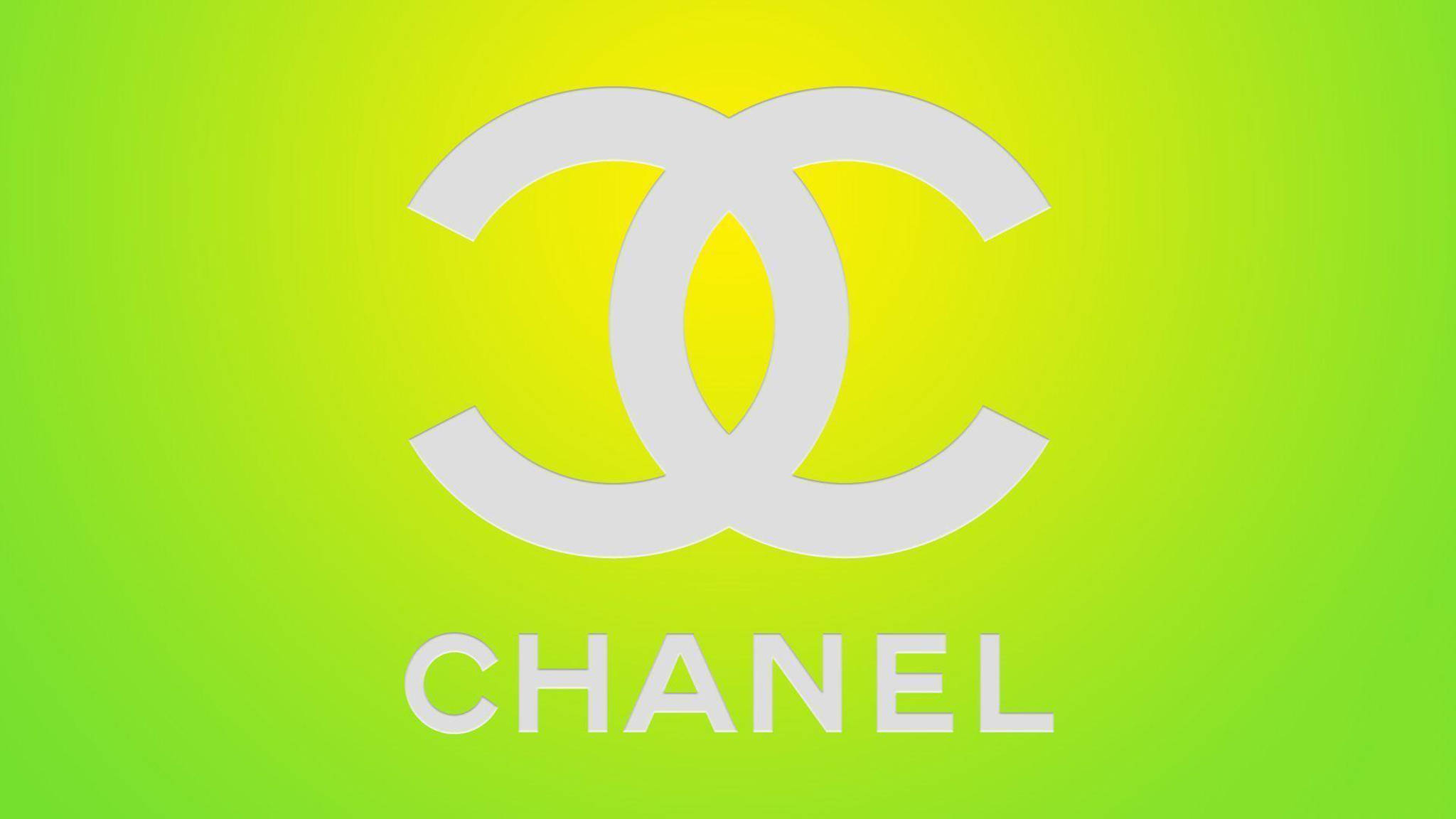 香奈兒標誌 桌布 壁紙 — 一個大膽的白色 Chanel 標誌，居中在從黃色到萊姆綠的鮮豔漸變背景上。