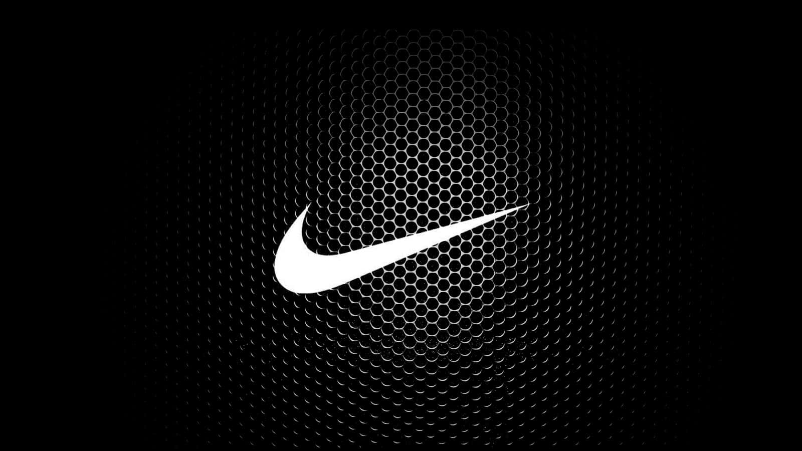 1600 X 900 Black 桌布 壁紙 — 一個大膽的白色Nike swoosh標誌居中在黑色六角網格背景上，帶有微妙的放射狀照明。