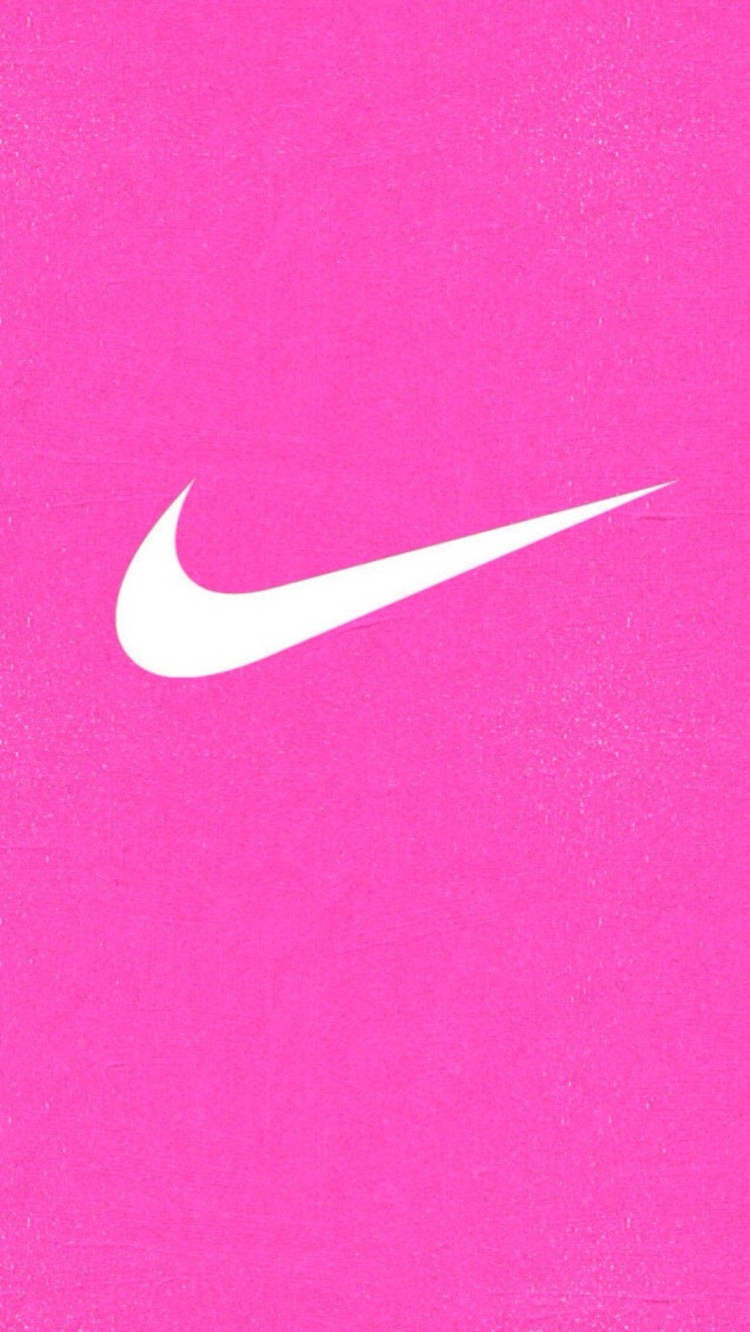 Nike 桌布 壁紙 — 一個大膽的白色Nike swoosh標誌，居中在充滿活力的紋理粉紅色背景上。