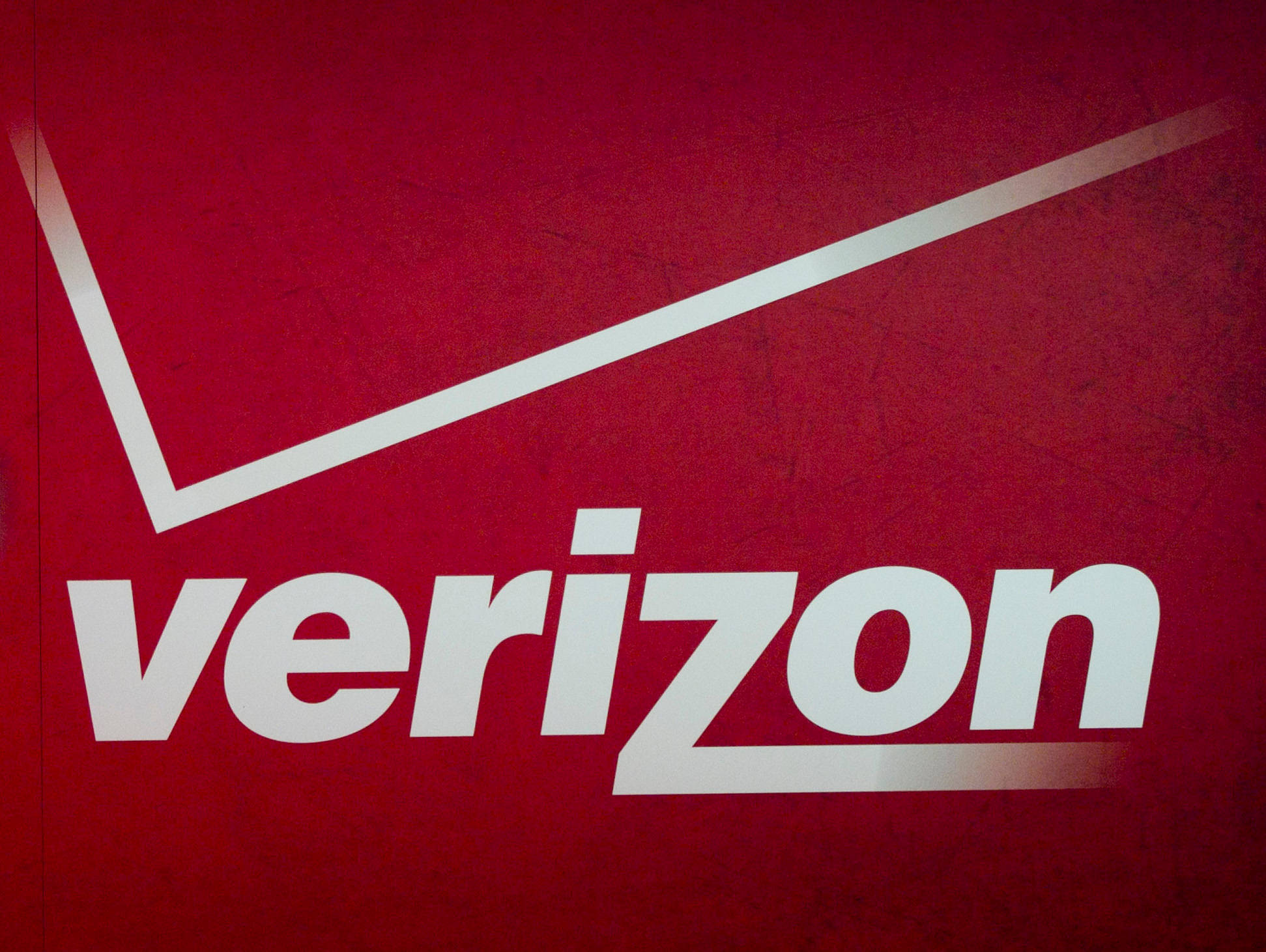 Verizon 桌布 壁紙 — 一個大膽的白色Verizon標誌，帶有對角線，位於有紋理的深紅色背景上。