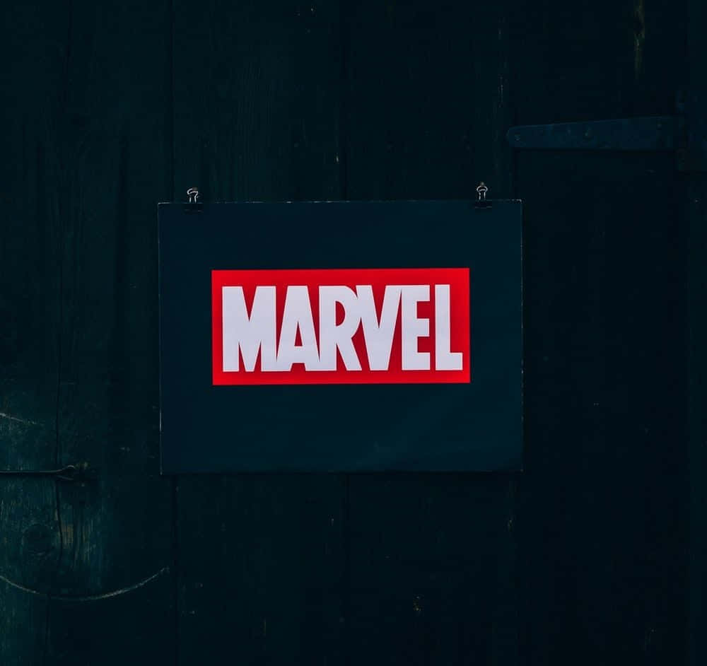 Best Marvel 桌布 壁紙 — 一個大膽的紅白Marvel標誌懸掛在帶有金屬鉸鏈的深色風化木門中央。