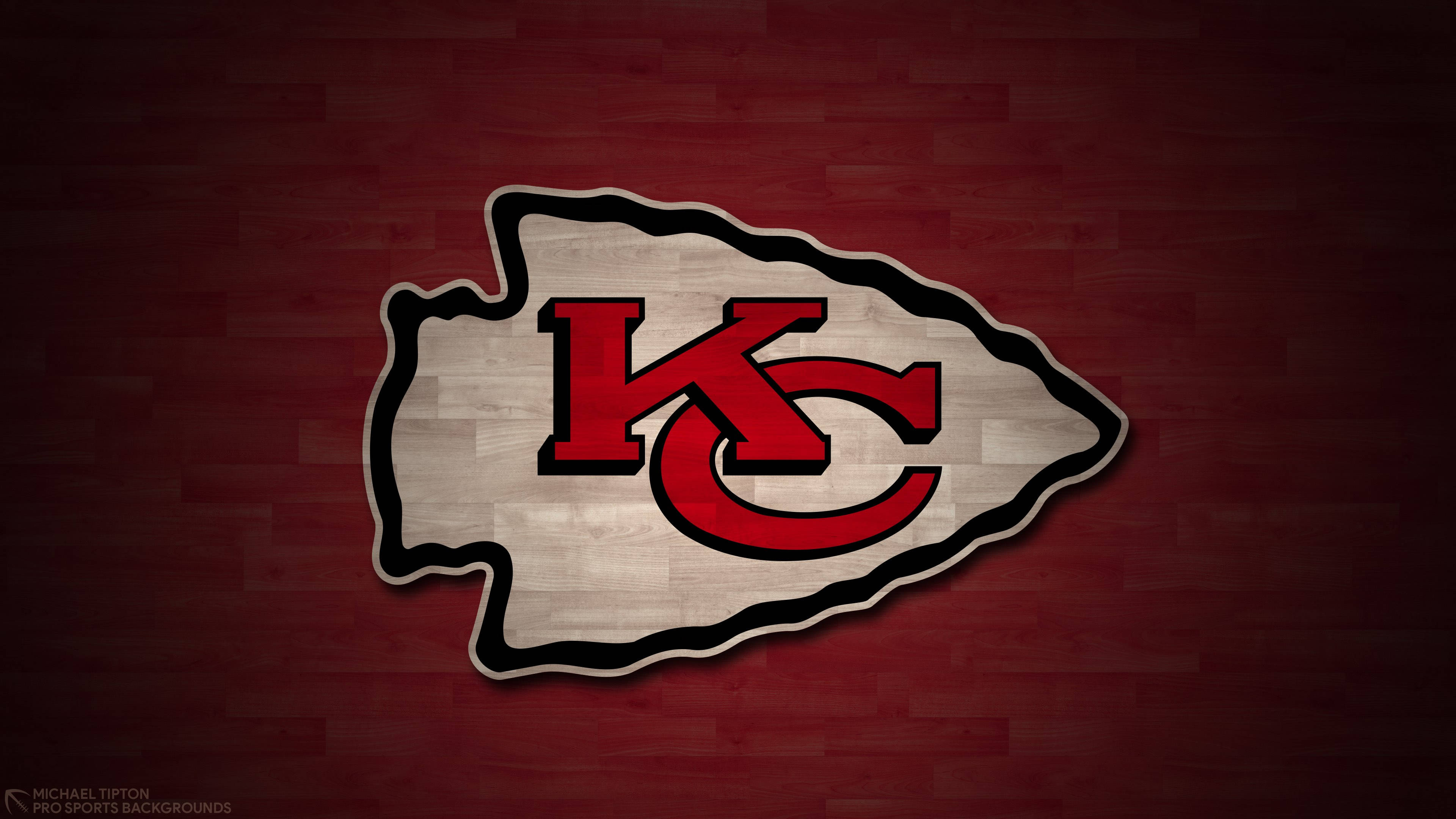 Kansas City Chiefs Logo 桌布 壁紙 — 一個大膽的紅白相間堪薩斯城酋長隊標誌，帶有黑色輪廓，居中放置在紋理深紅色木質背景上。