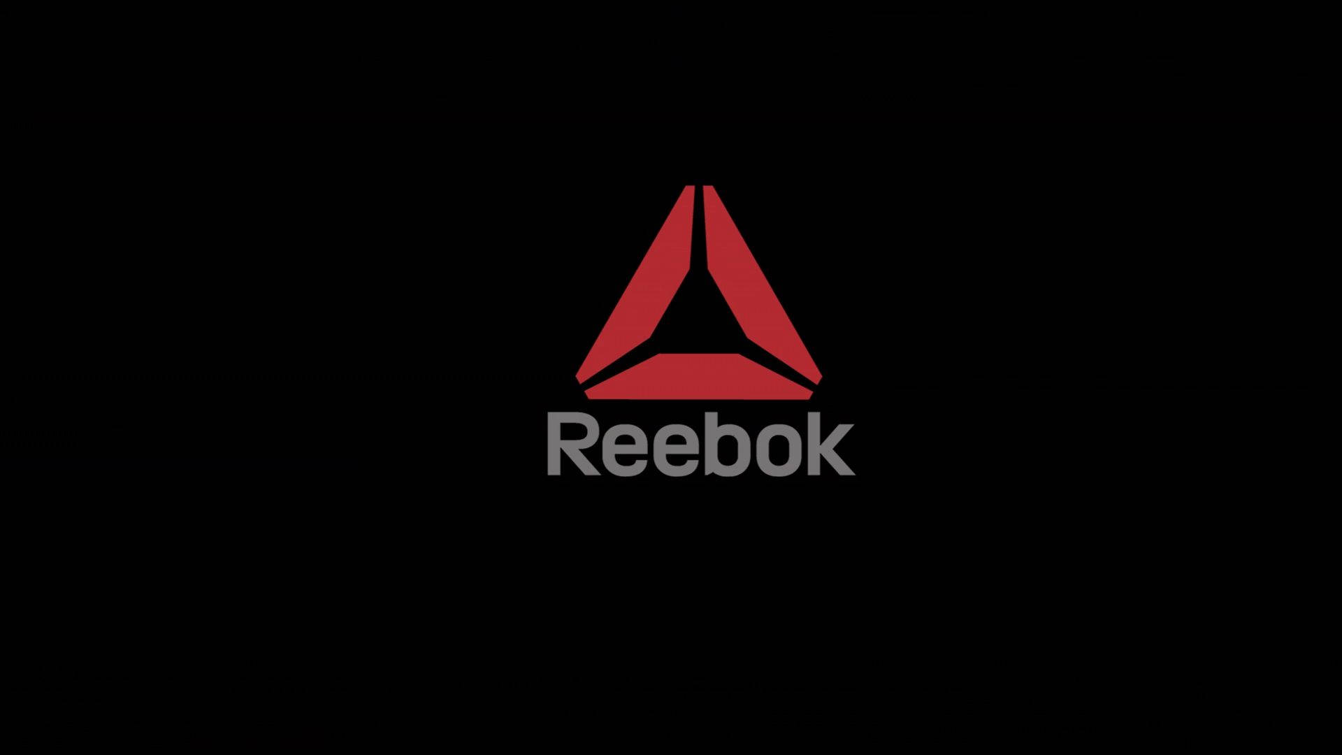 Reebok 桌布 壁紙 — 一個大膽的紅色 Reebok 標誌居中在純黑色背景上，品牌名稱以灰色文字顯示在下方。