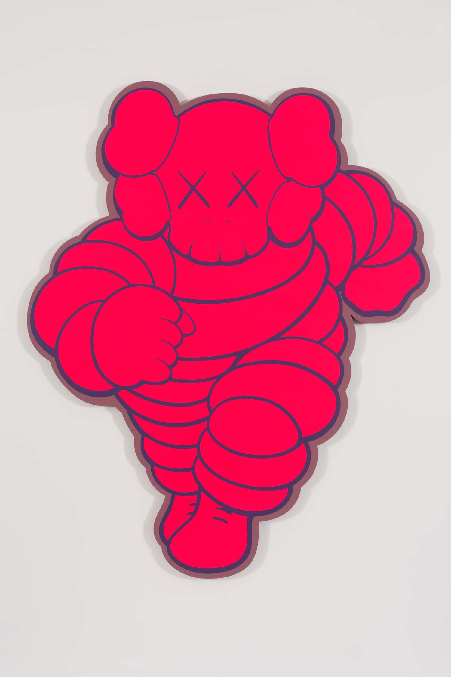 KAWS 桌布 壁紙 — 一個大膽的紅色KAWS熊雕塑，帶有X形眼睛和蜷曲的四肢，立在純白牆前。