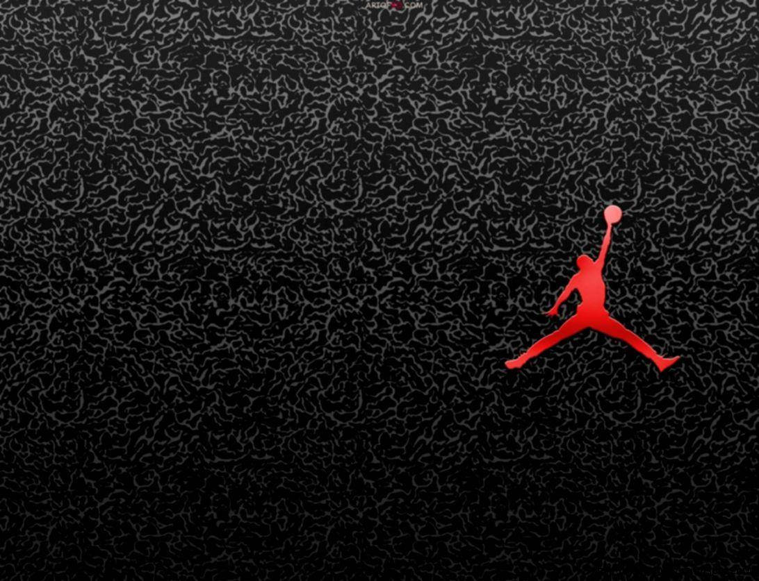 Air Jordan 桌布 壁紙 — 一個大膽的紅色剪影，描繪一名籃球運動員在半空中持球，背景為帶紋理的黑色。