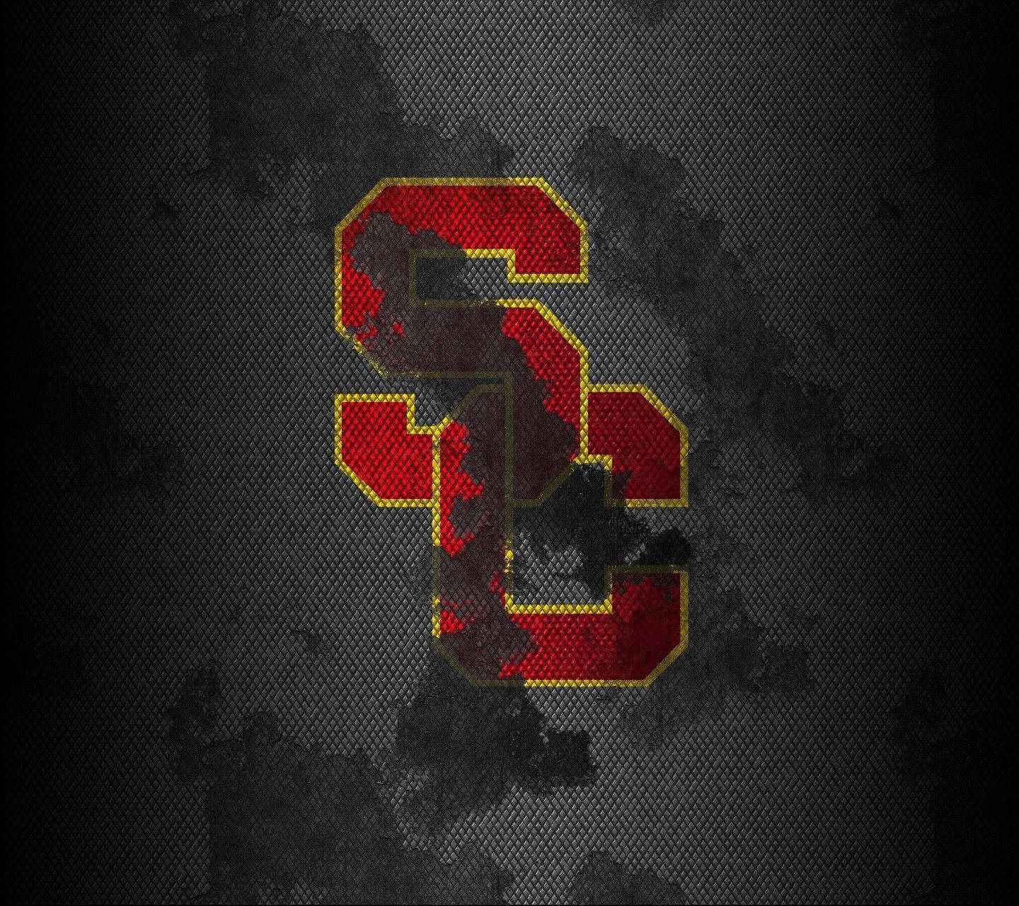 Usc 桌布 壁紙 — 一個大膽的紅色和金色交織SC標誌，帶有紋理布料外觀，在深灰色網格背景上脫穎而出。